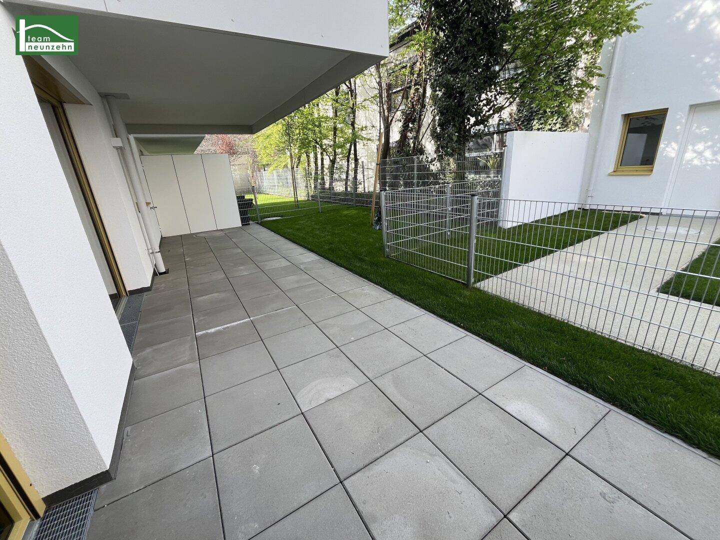 Gepflasterte Terrasse mit angrenzender Rasenfläche und Zaun im Außenbereich.