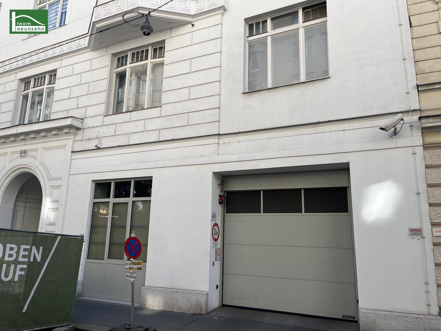 Gebäudefassade mit Garagentor und Fenstern, umgeben von städtischer Architektur.