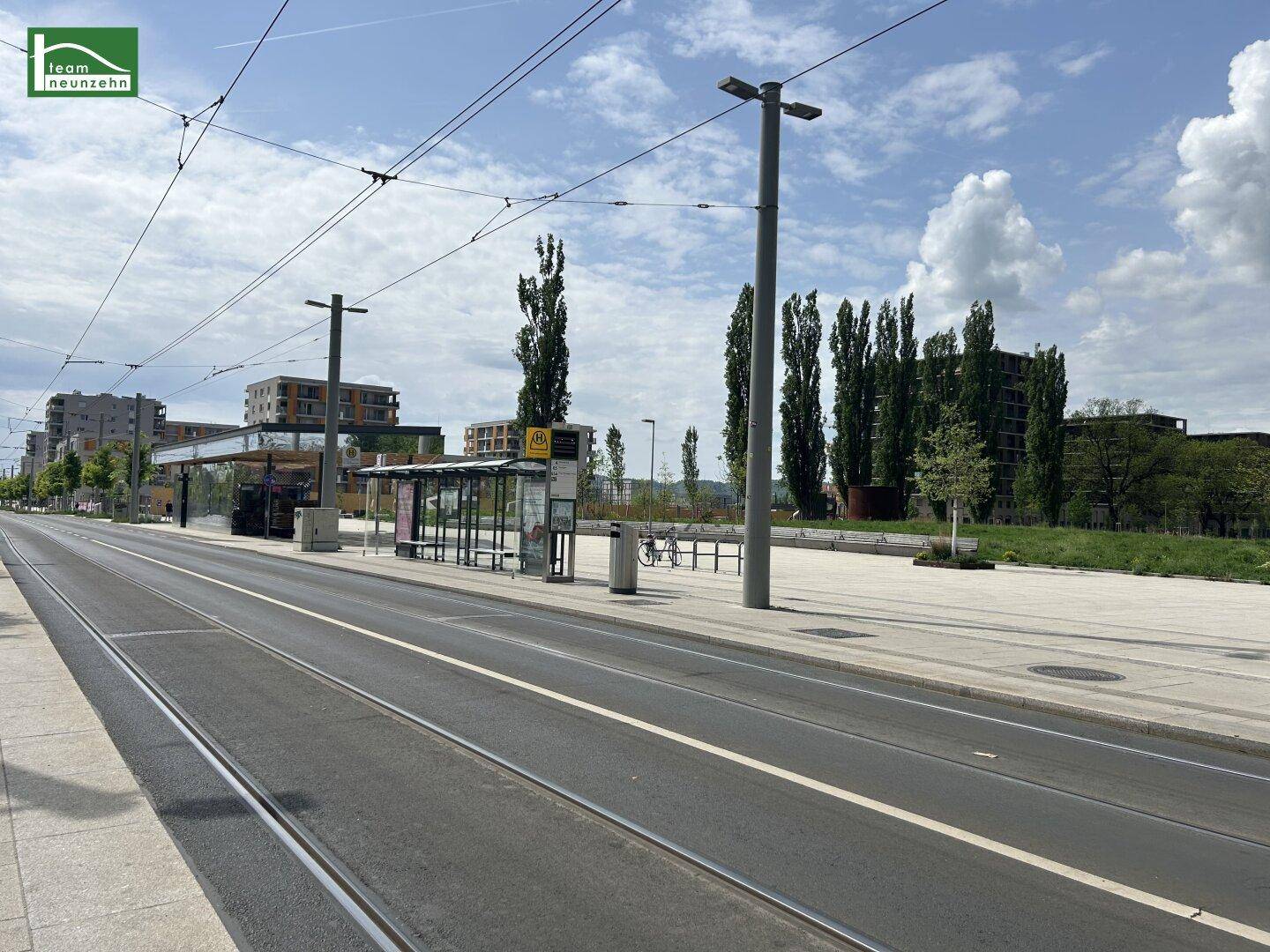 Eine moderne Straße mit Straßenbahnschienen und einer Haltestelle in der Nähe.