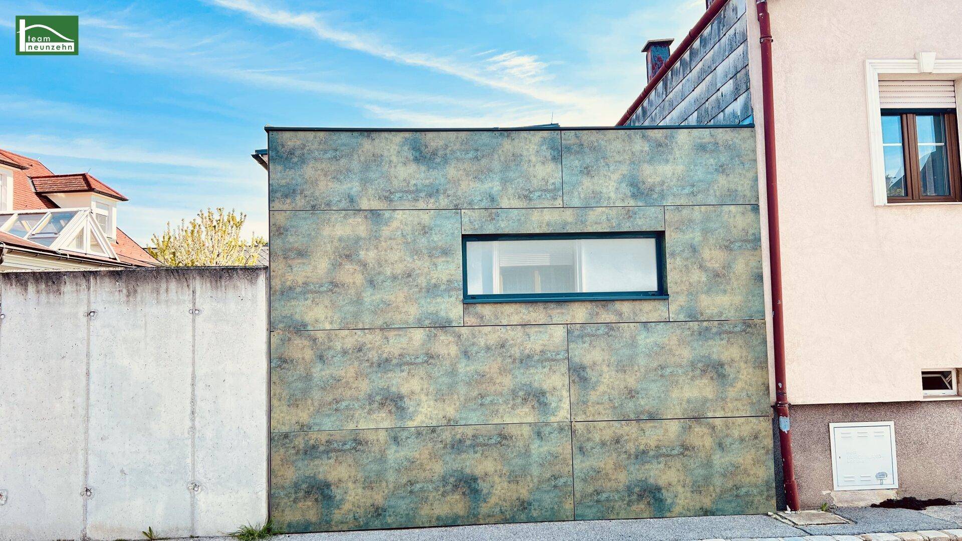 Detailansicht einer modernen Fassade mit strukturierten Paneelen und horizontalem Fenster.