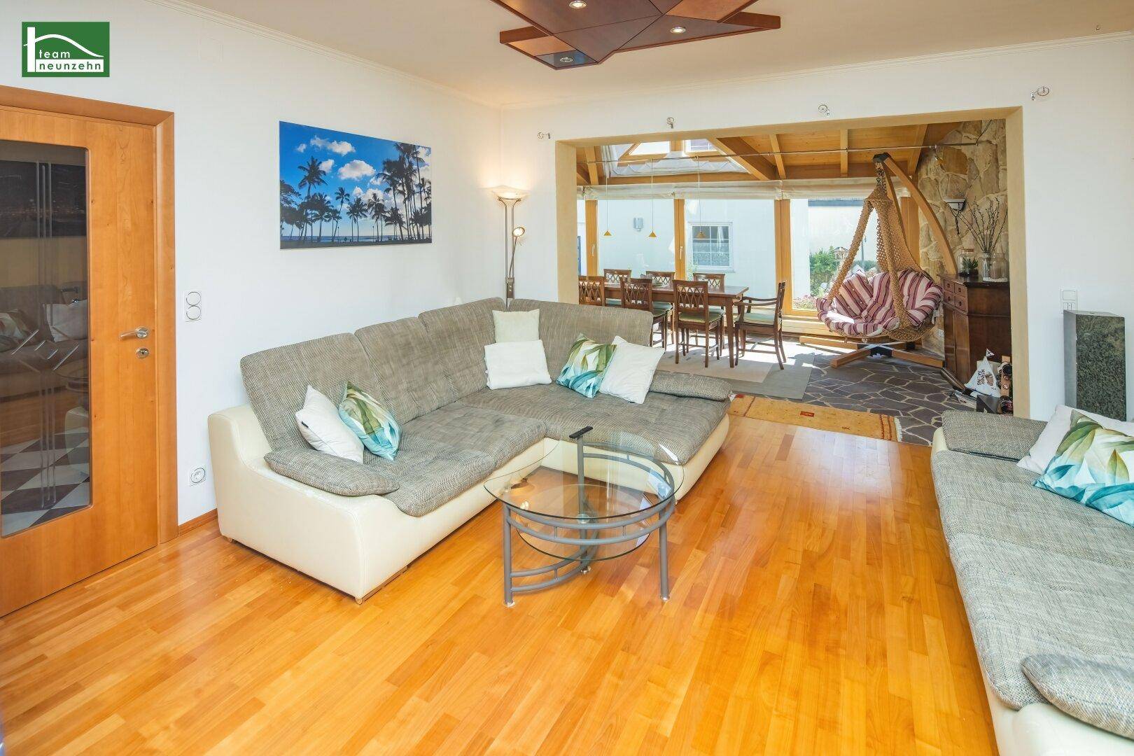Geräumiges Wohnzimmer mit Holzboden und offenem Übergang zu einem hellen Essbereich.