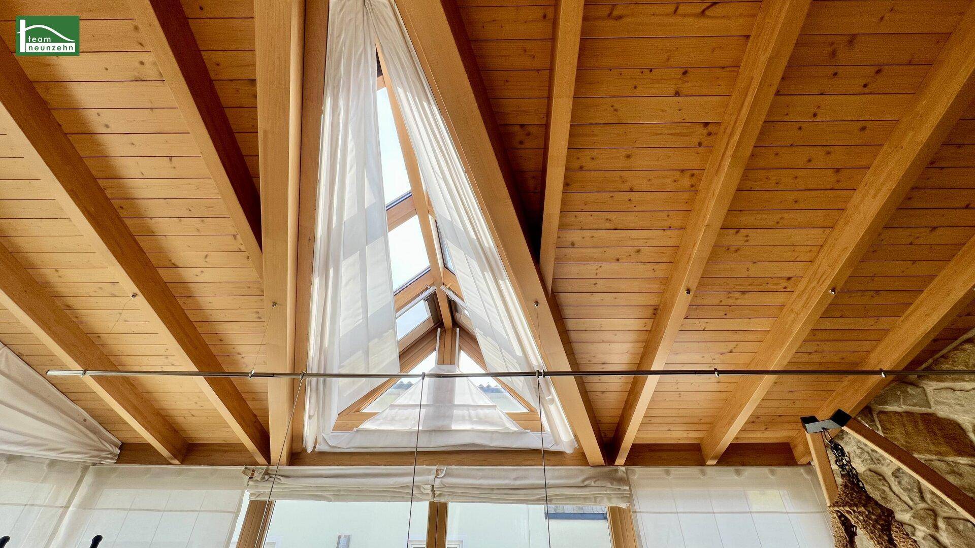 Decke eines Wintergartens mit sichtbaren Holzbalken und Dachfenstern.