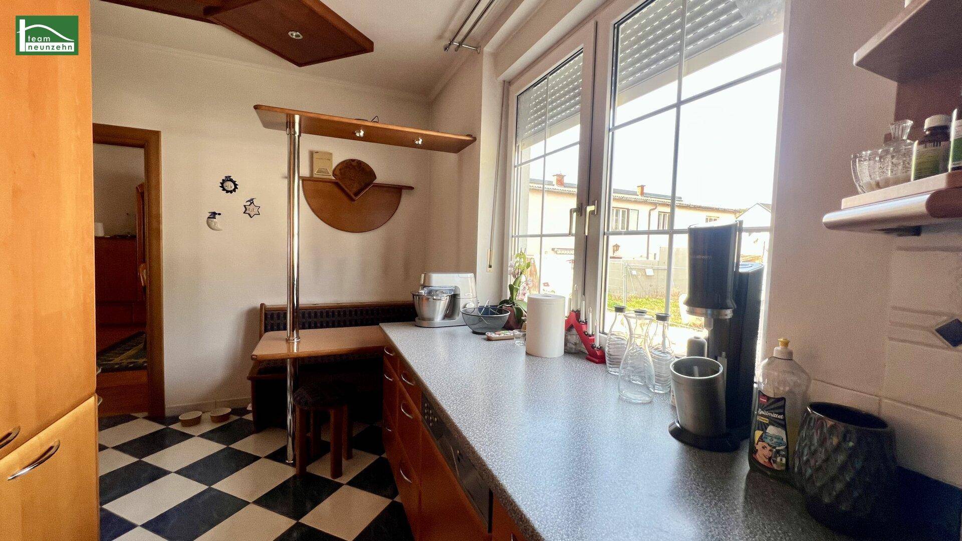 Küchenbereich mit Fenster, Arbeitsfläche und kleiner Essecke.