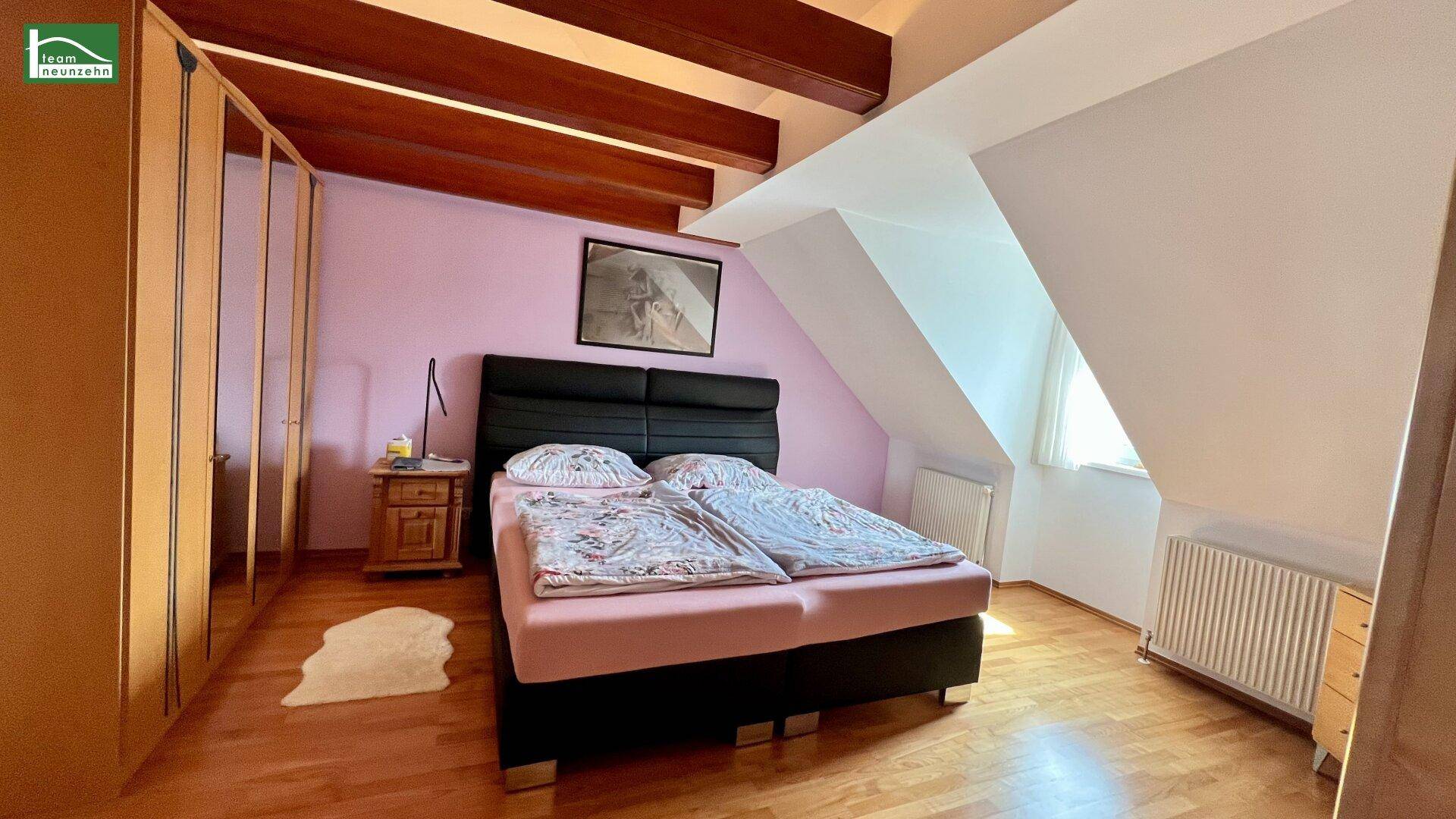 Schlafzimmer mit Holzboden, Doppelbett und Einbauschränken unter der Dachschräge.