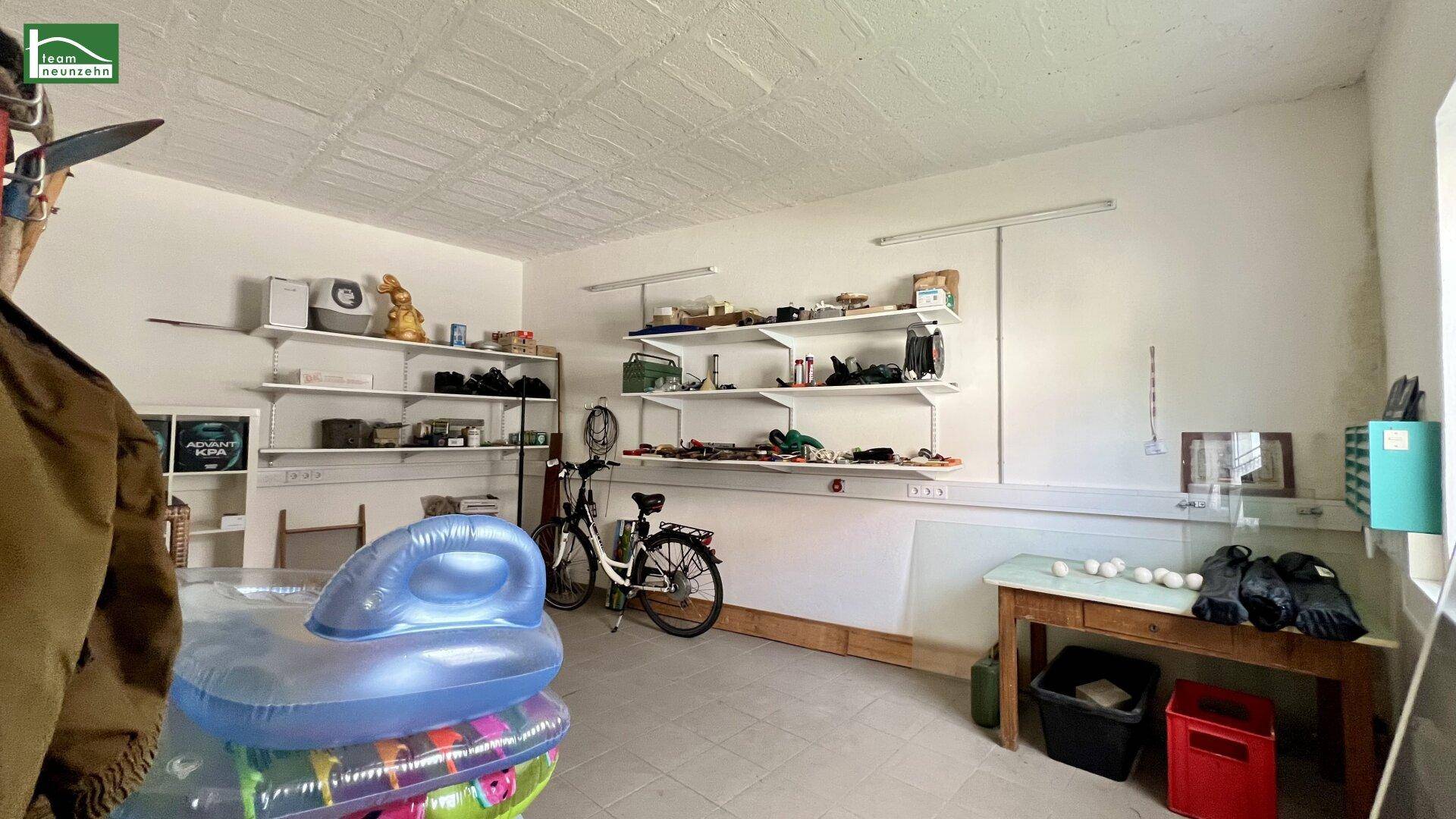 Geräumige Garage mit Regalen, Fahrrad und Stauraum für diverse Gegenstände.