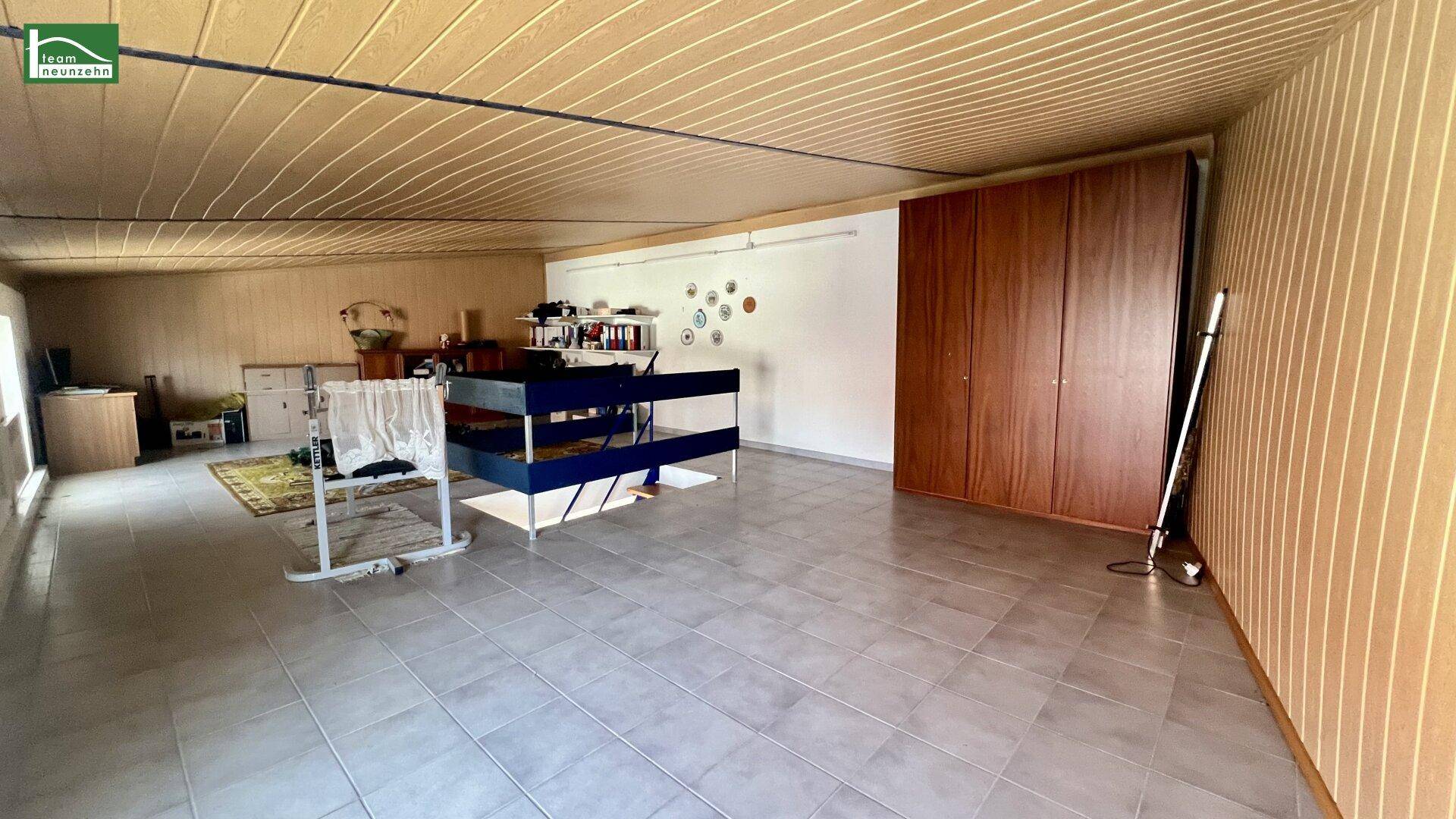 Großer Abstellraum mit Fliesenboden, Holzverkleidung und viel Stauraum.