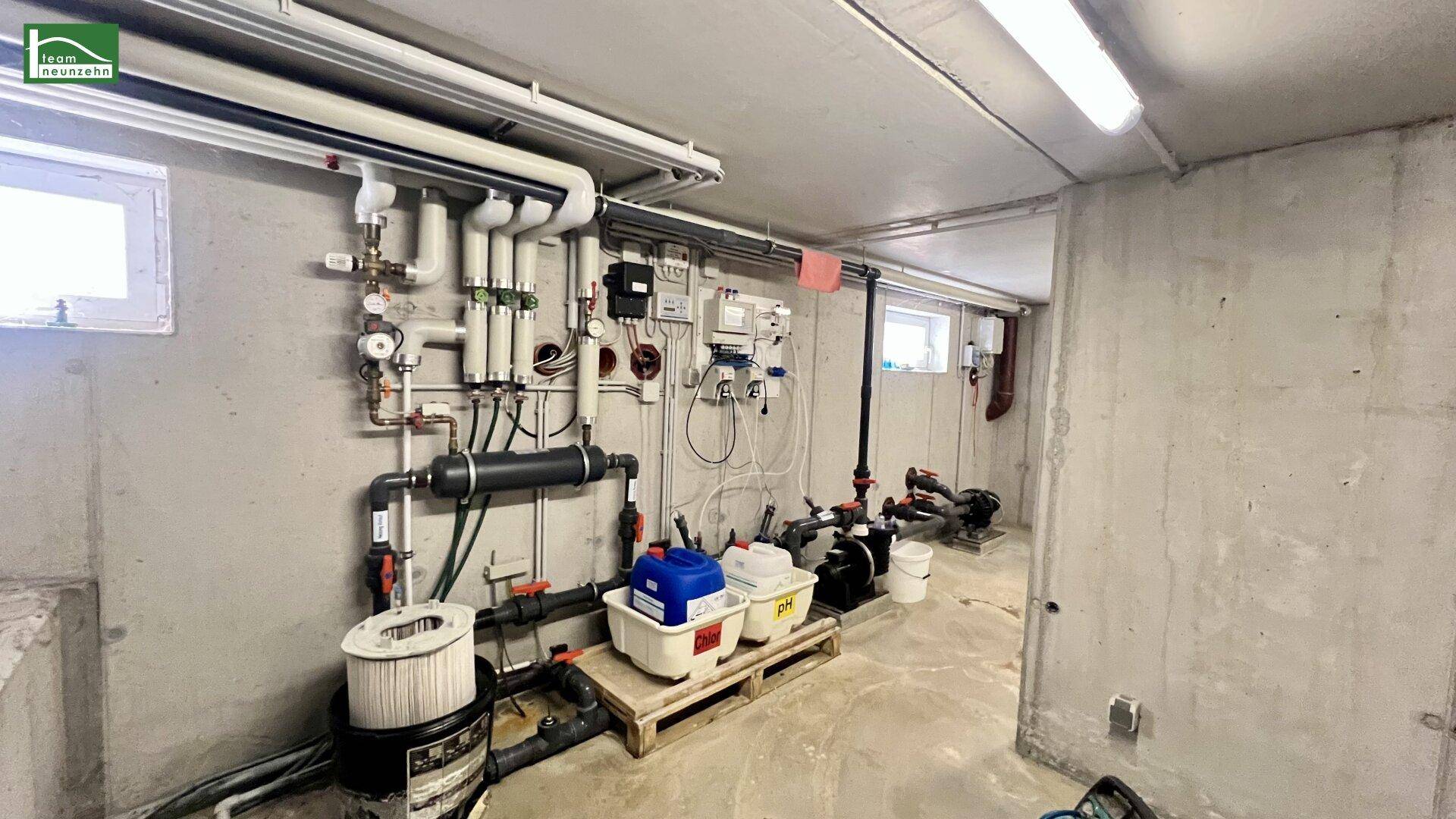 Technikraum im Keller mit zahlreichen Rohren, Filtern und Pumpen.