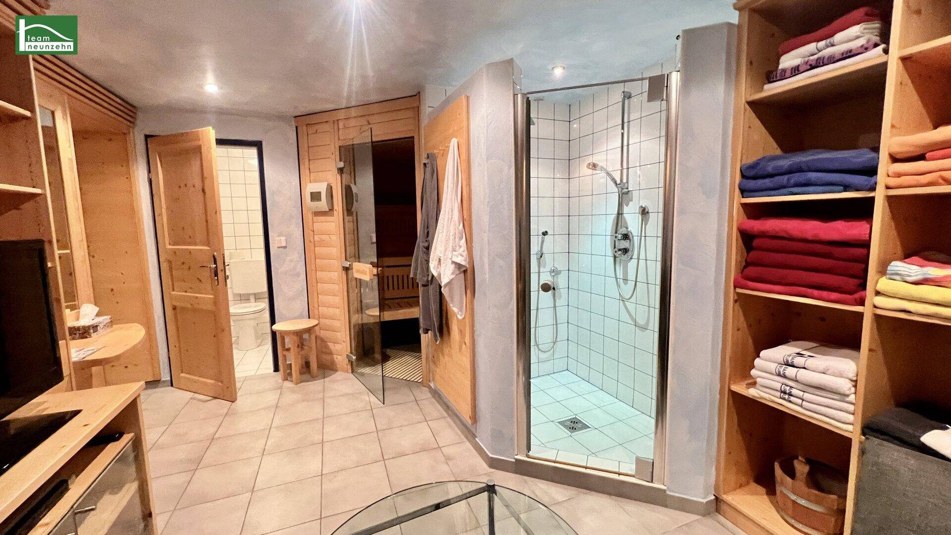 Wellnessbereich mit Sauna, Dusche und Regalen für Handtücher.