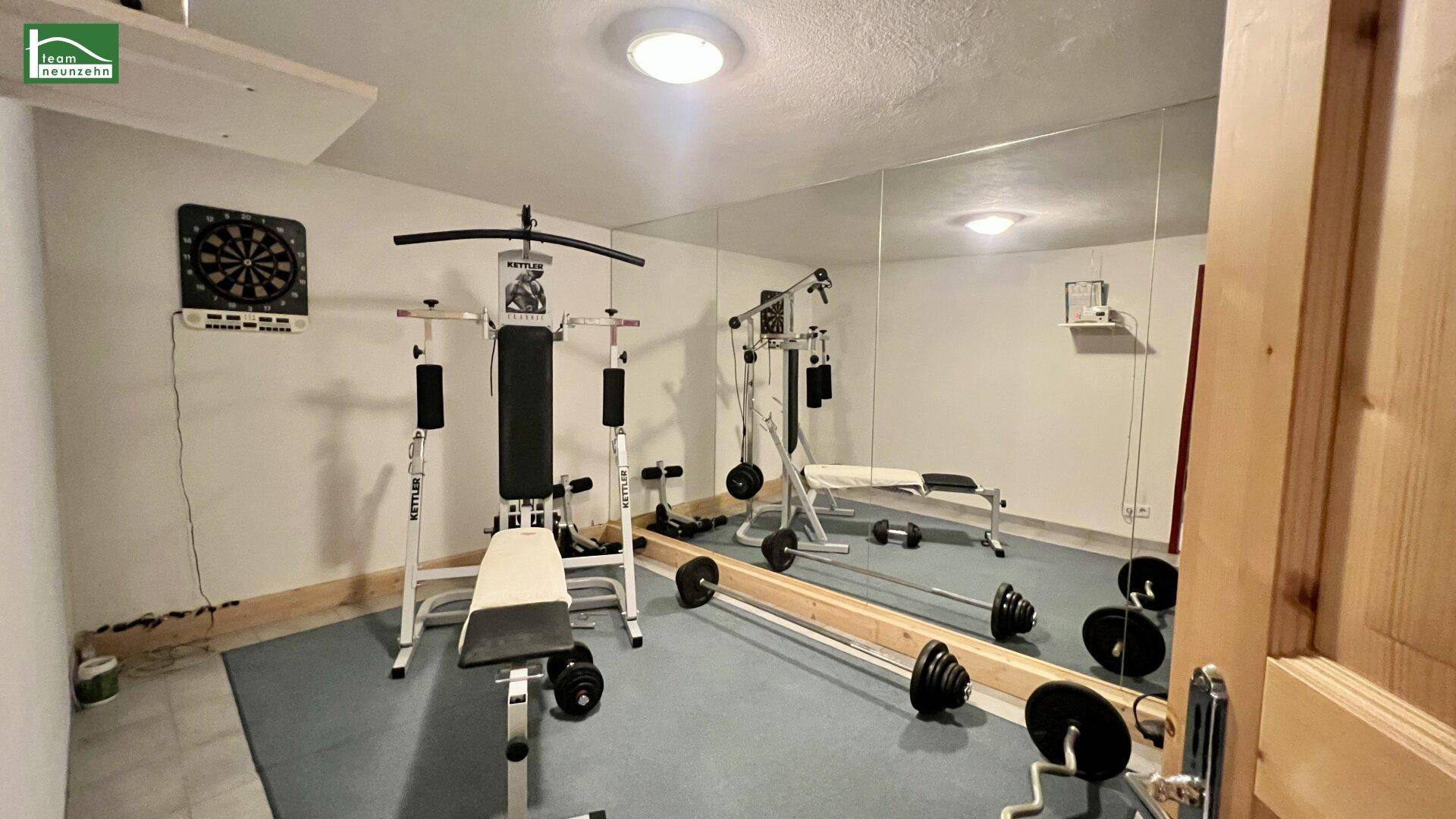 Fitnessraum mit verschiedenen Trainingsgeräten und großer Spiegelwand.