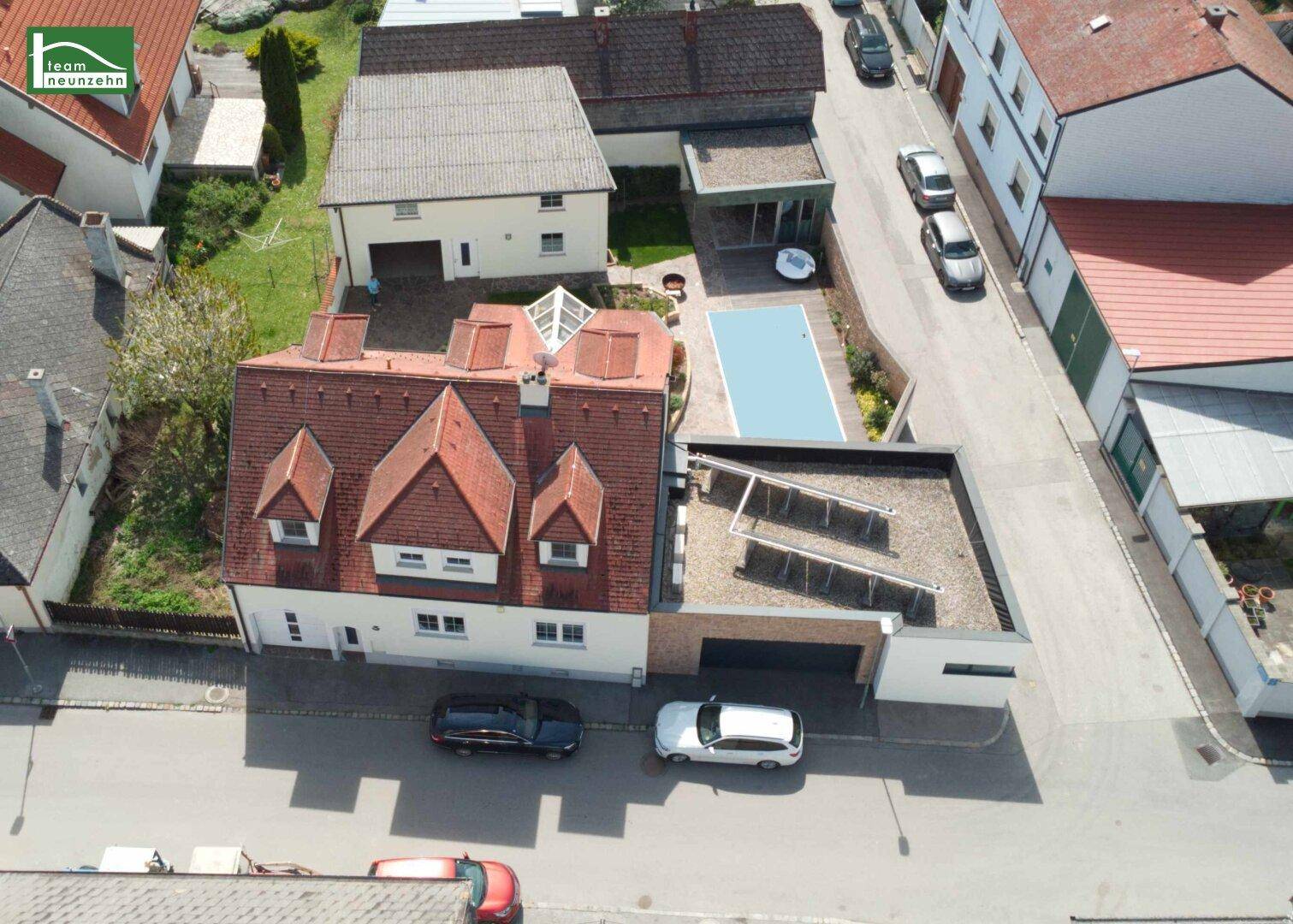 Luftaufnahme des Anwesens mit Pool, Solaranlage und umliegender Bebauung.