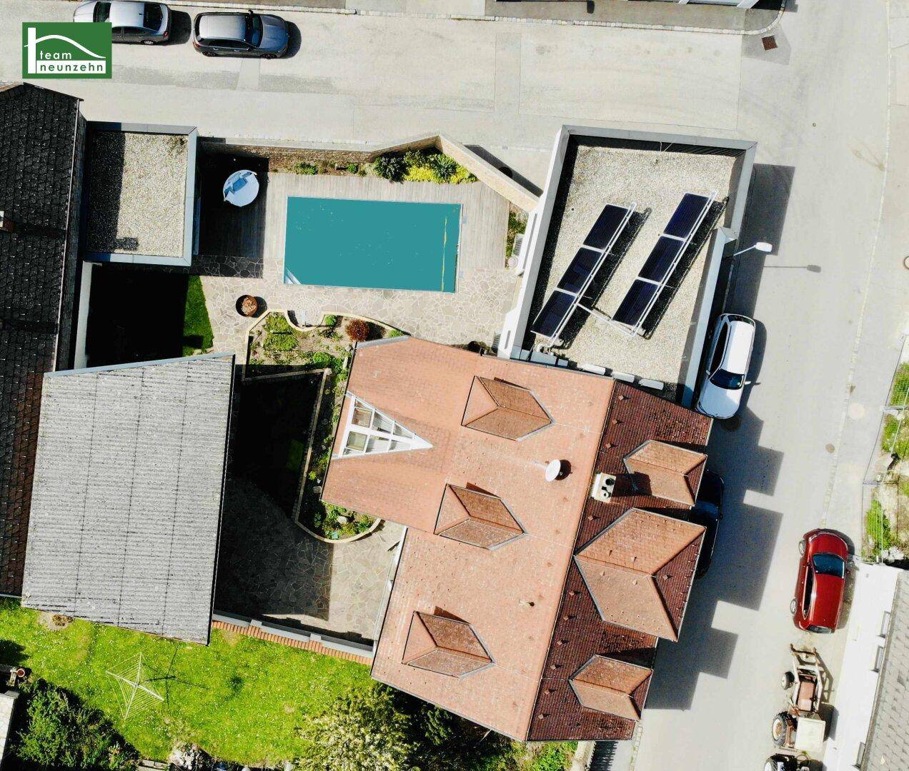 Luftaufnahme eines Hauses mit Swimmingpool im Garten und Solaranlage auf dem Dach.