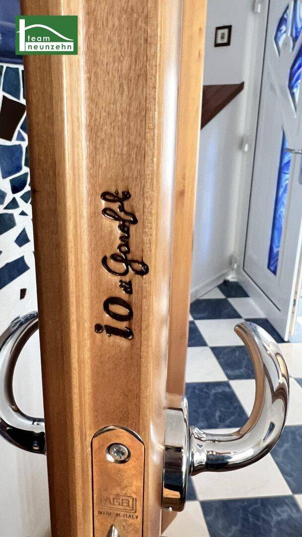 Nahaufnahme eines Holz-Türrahmens mit dekorativem Griff und Gravur.