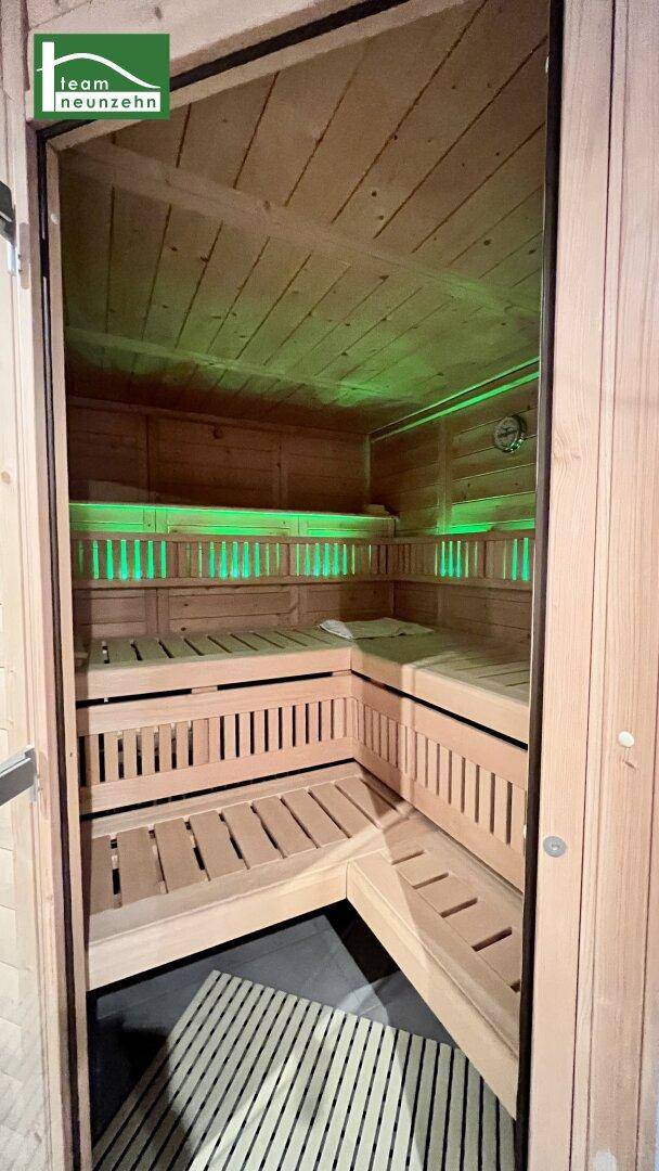 Innenansicht der Sauna mit Holzverkleidung, Sitzbänken und stimmungsvoller Beleuchtung.