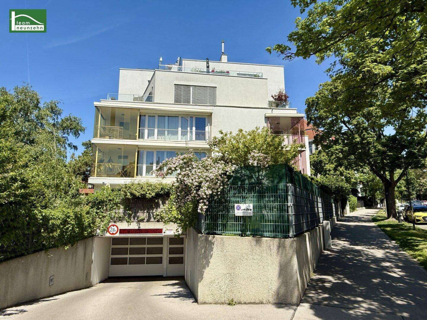 Moderne Wohnanlage mit Balkonen und Zufahrt zur Tiefgarage in grüner Umgebung.