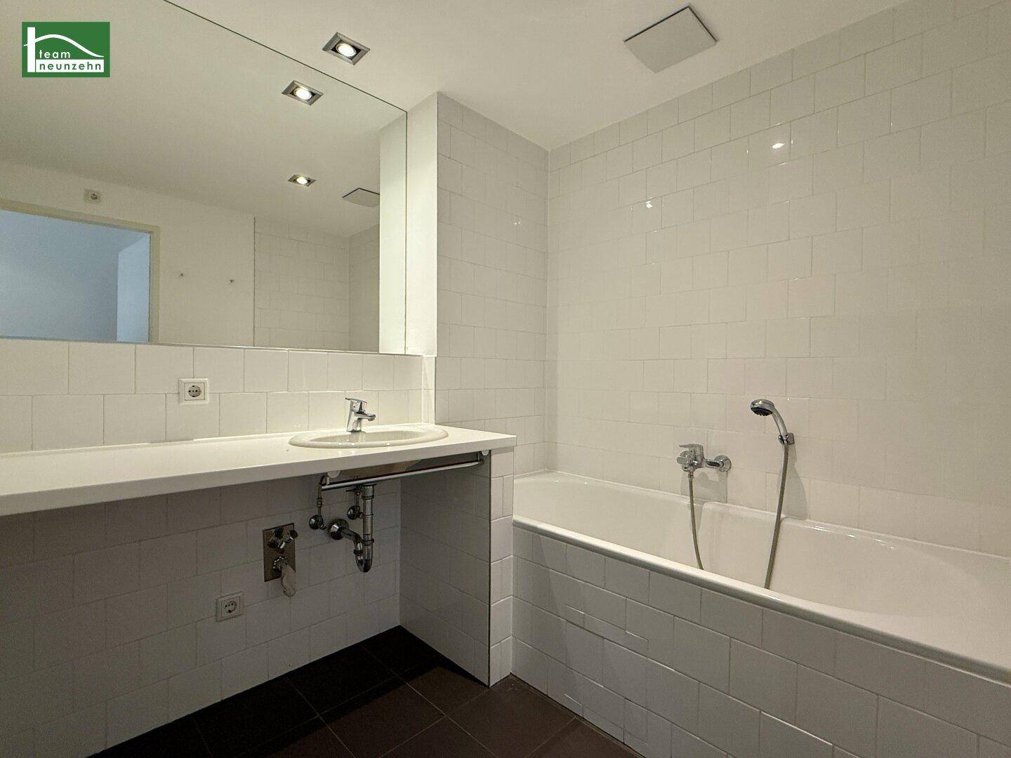 Modernes Badezimmer mit Badewanne, Einzelwaschbecken und weißen Fliesen.