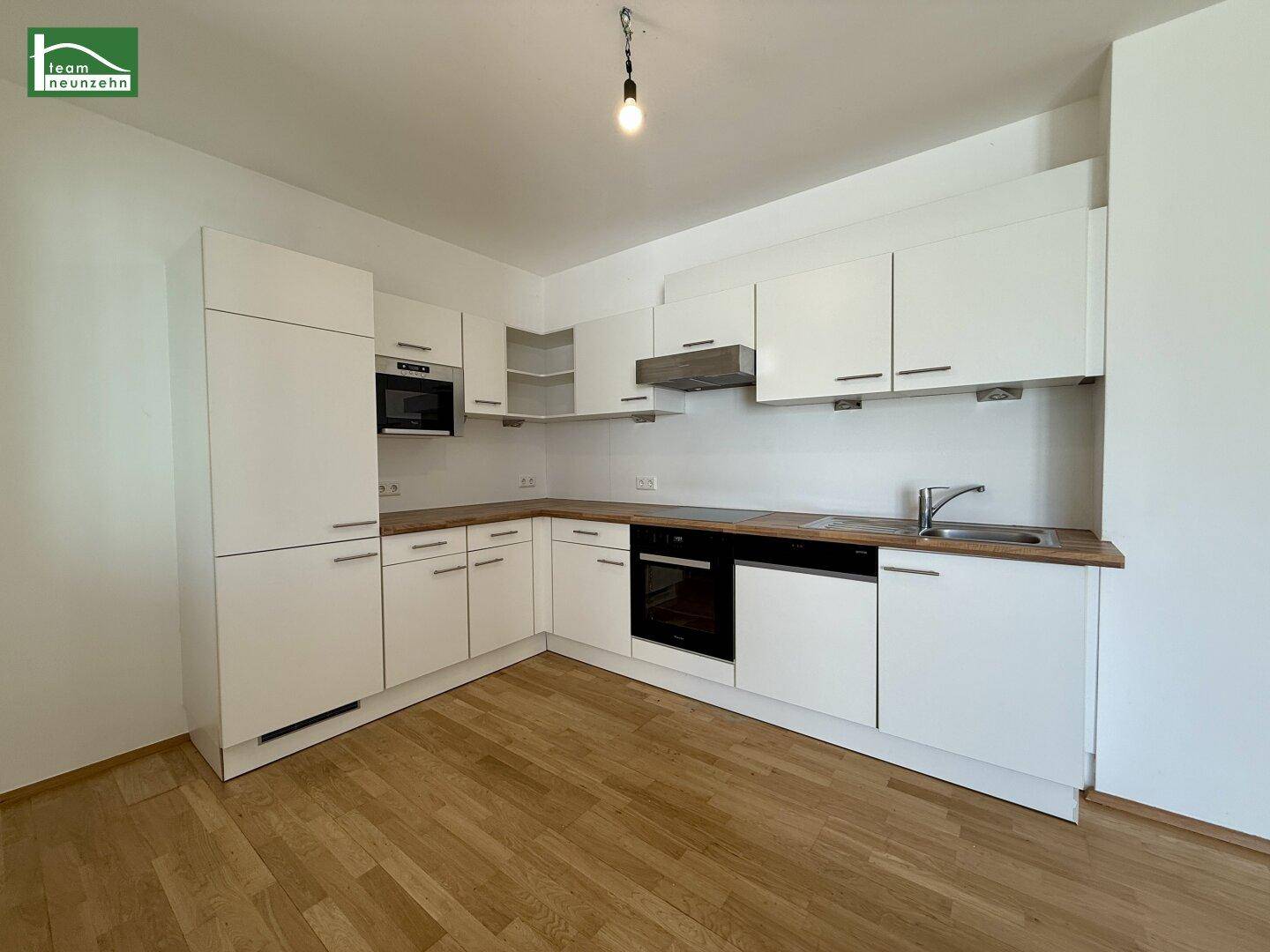 Moderne Einbauküche in Weiß mit Holz-Arbeitsplatte und integrierten Geräten.