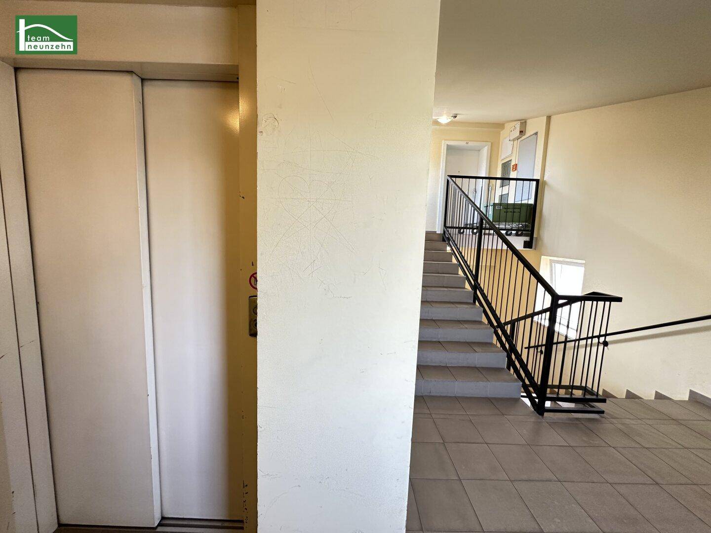 Moderner Hausflur mit Aufzug und Treppenhaus, hell und funktional gestaltet für Bewohner.