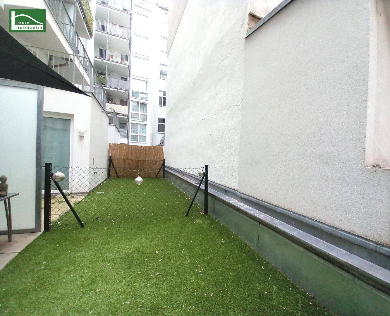 Kleiner privater Gartenbereich mit Kunstrasen und Sichtschutz.