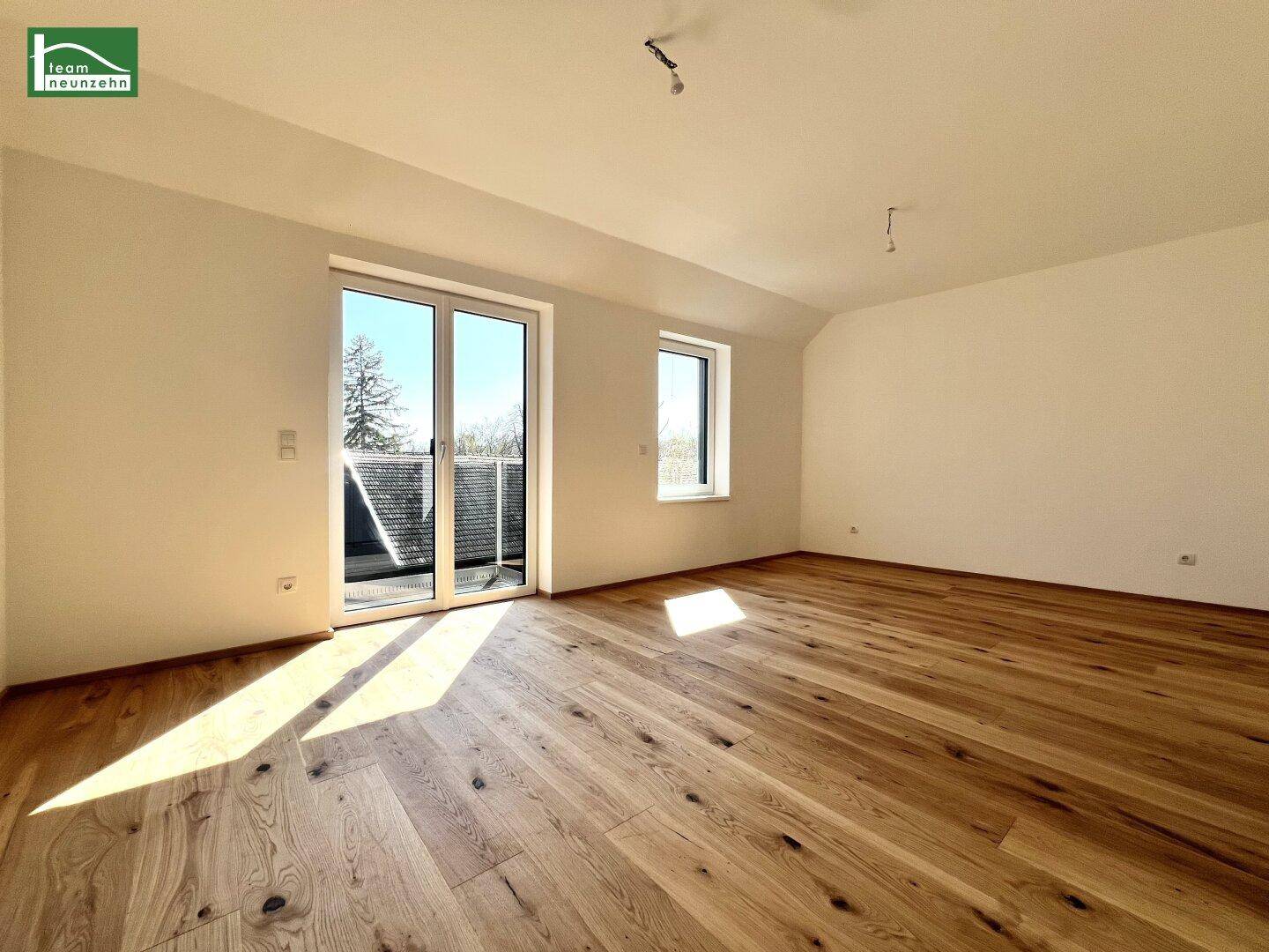 Lichtdurchflutetes Zimmer mit Holzboden, Balkonzugang und Dachschräge, ideal als Schlafzimmer.