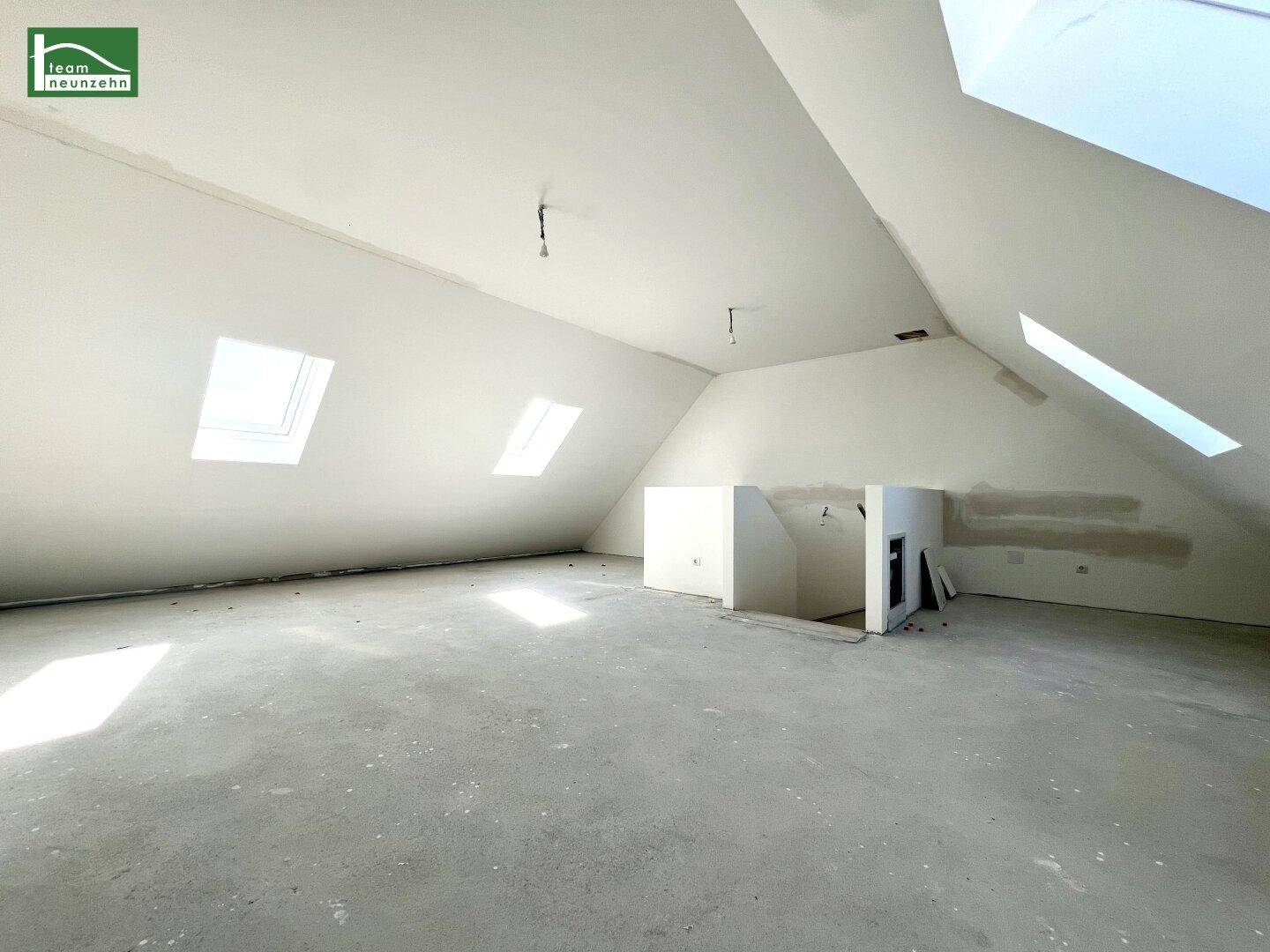 Geräumiger Dachbodenraum mit schrägen Decken, mehreren Dachfenstern und Betonboden, ideal für Ausbau.
