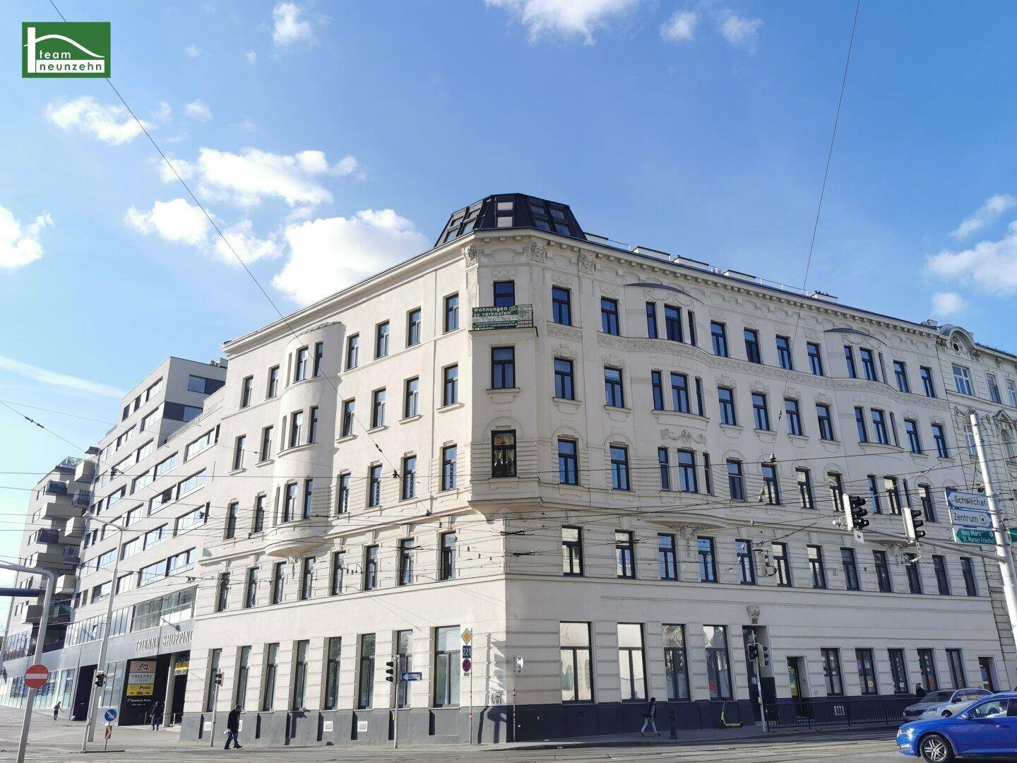 Elegantes Eckgebäude in der Stadt mit klassischer Architektur und vielen Fenstern unter blauem Himmel.