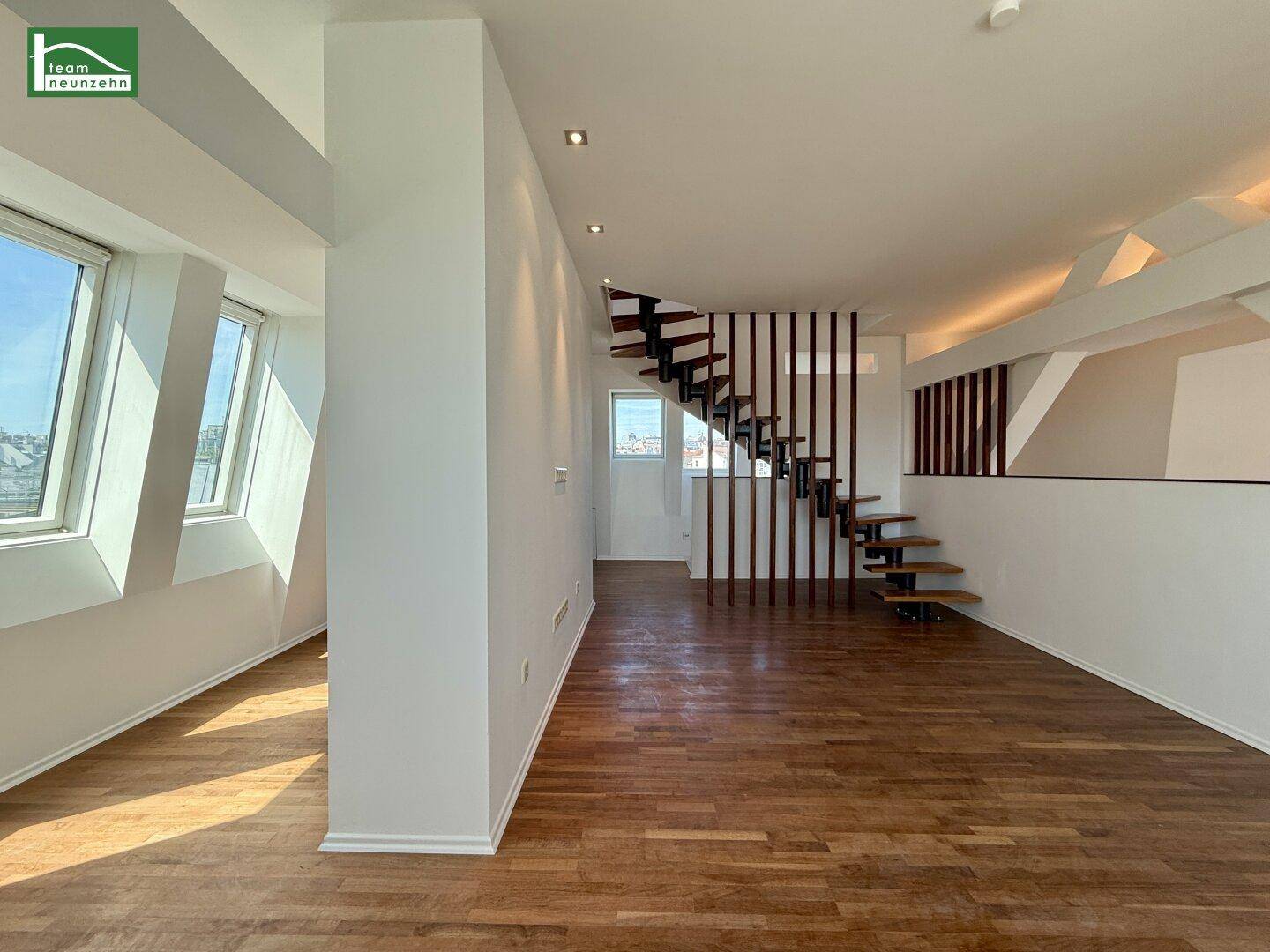 Heller Wohnbereich mit moderner Holztreppe, Parkettboden und großen Fenstern mit Stadtblick.