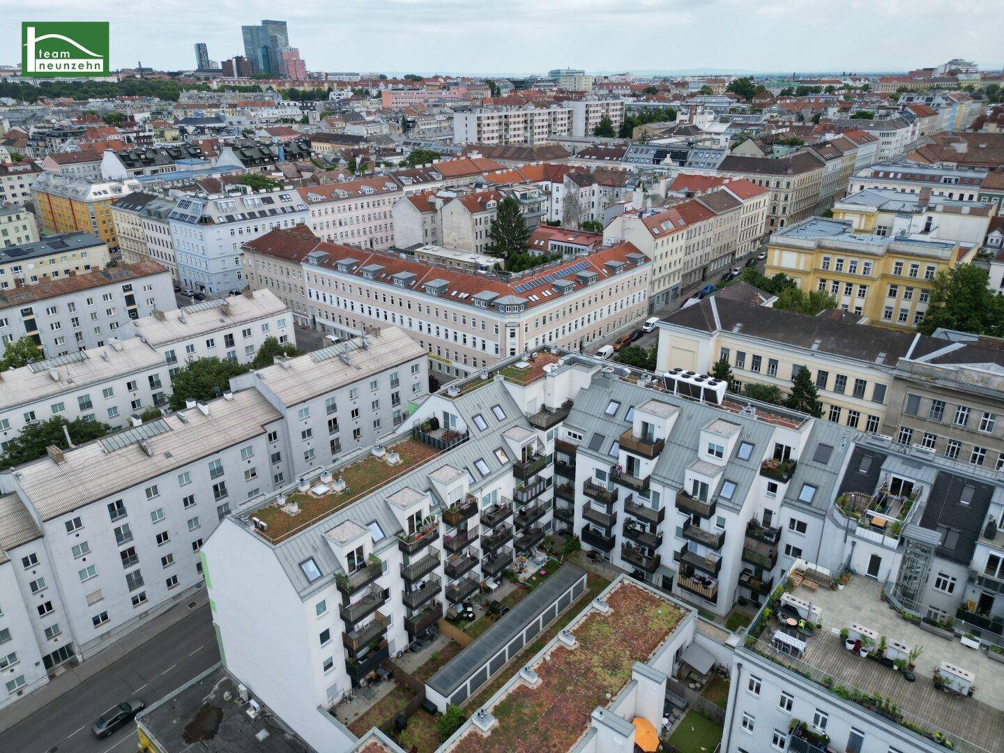 Weitläufige Luftaufnahme eines städtischen Wohngebiets mit vielen modernen Gebäuden und Dachterrassen.