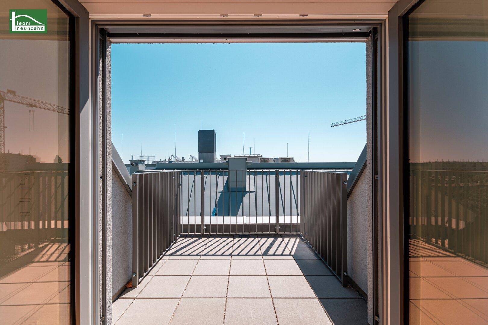 Blick von innen auf einen kleinen Balkon mit Metallgeländer und Stadtblick.