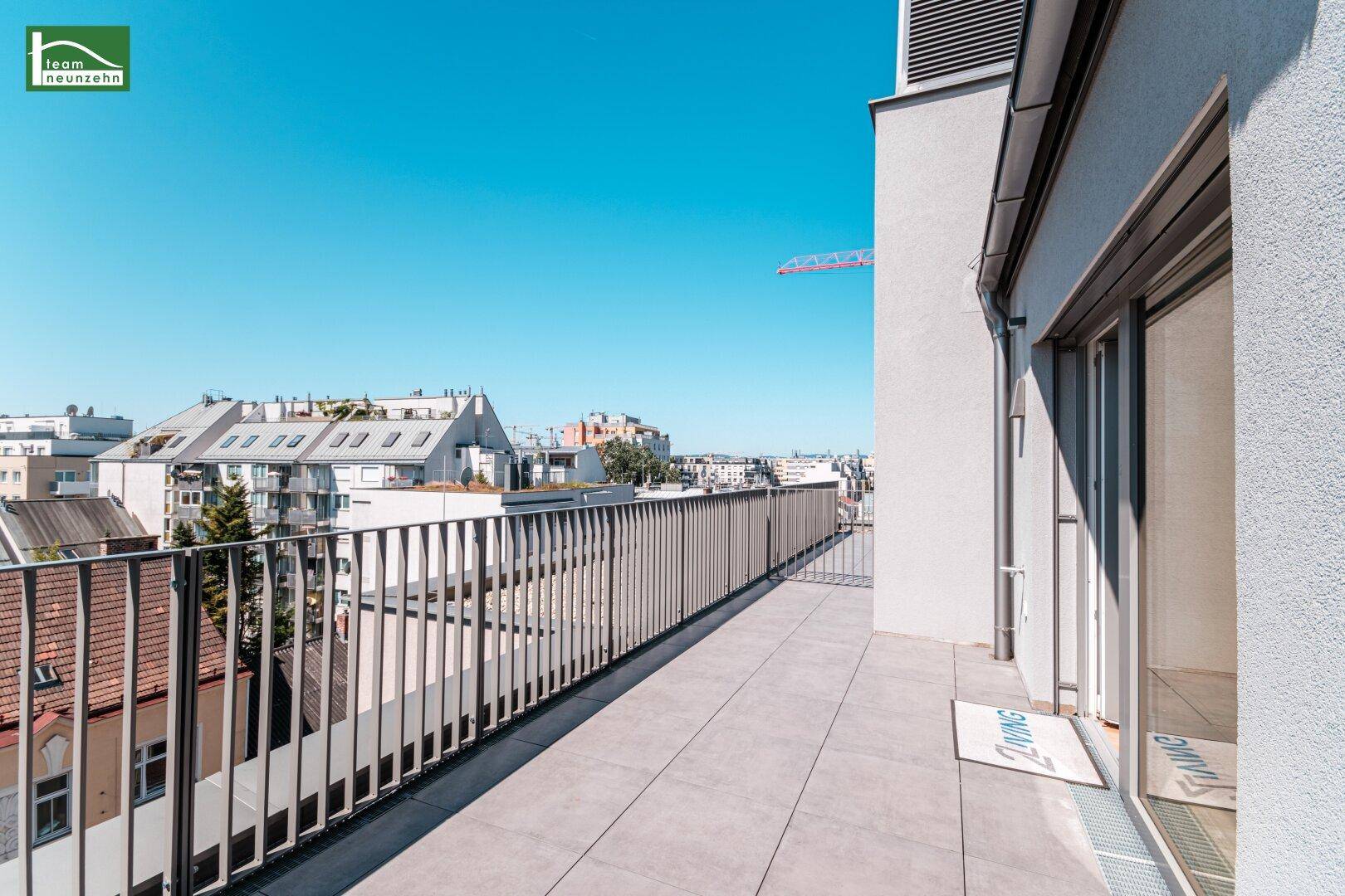 Lange Dachterrasse mit Metallgeländer und Blick auf die umliegende Stadtbebauung.