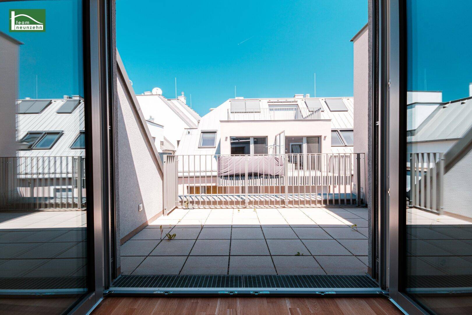 Geräumige Dachterrasse mit Fliesenboden und Blick auf umliegende Gebäude.
