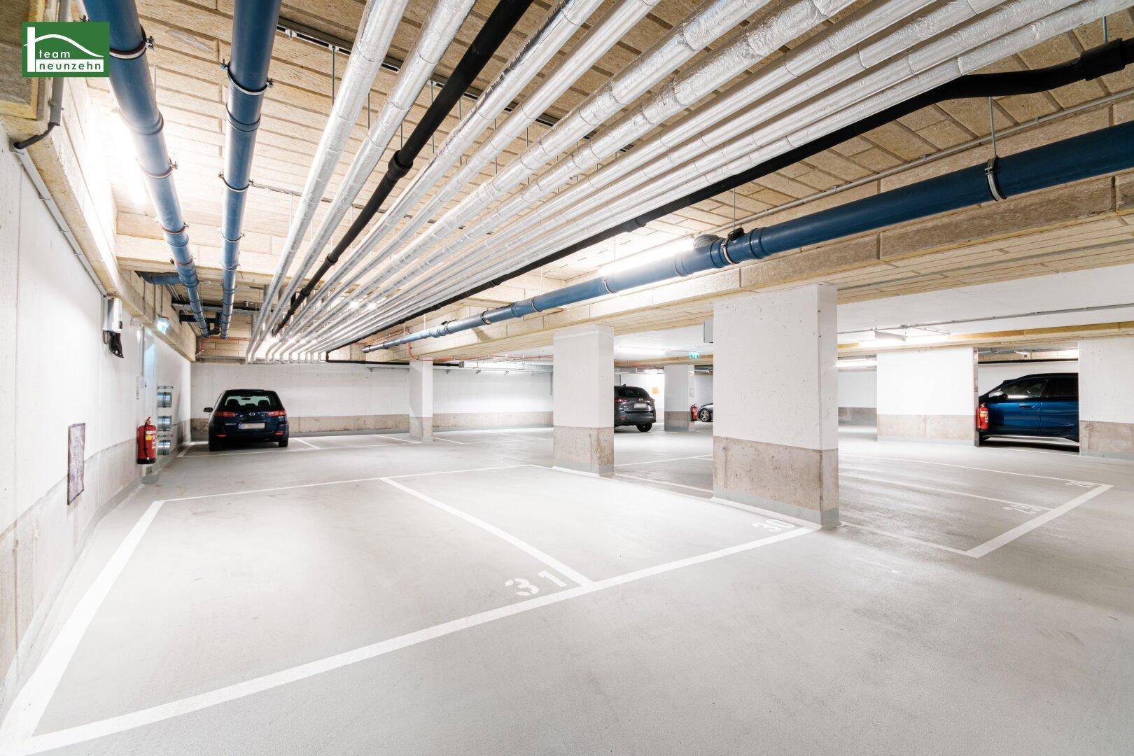 Moderne Tiefgarage mit markierten Stellplätzen und sichtbaren Deckeninstallationen.