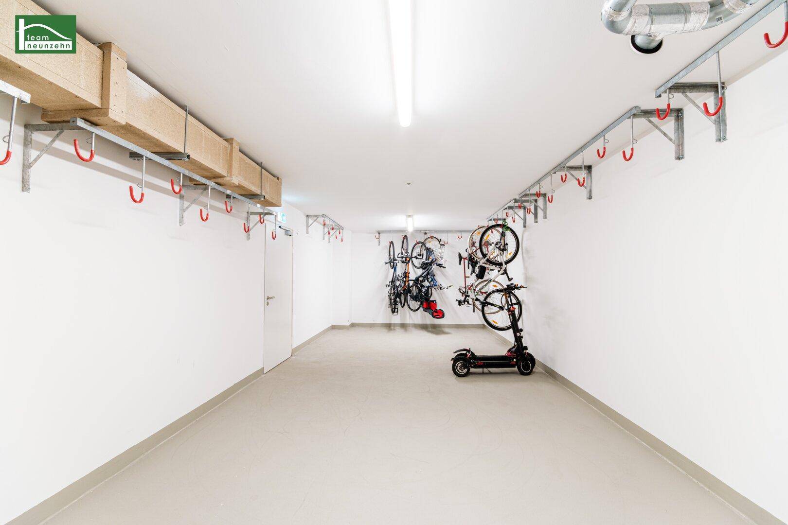 Geräumiger Fahrradraum mit praktischen Wandhalterungen für Fahrräder und einem E-Scooter.