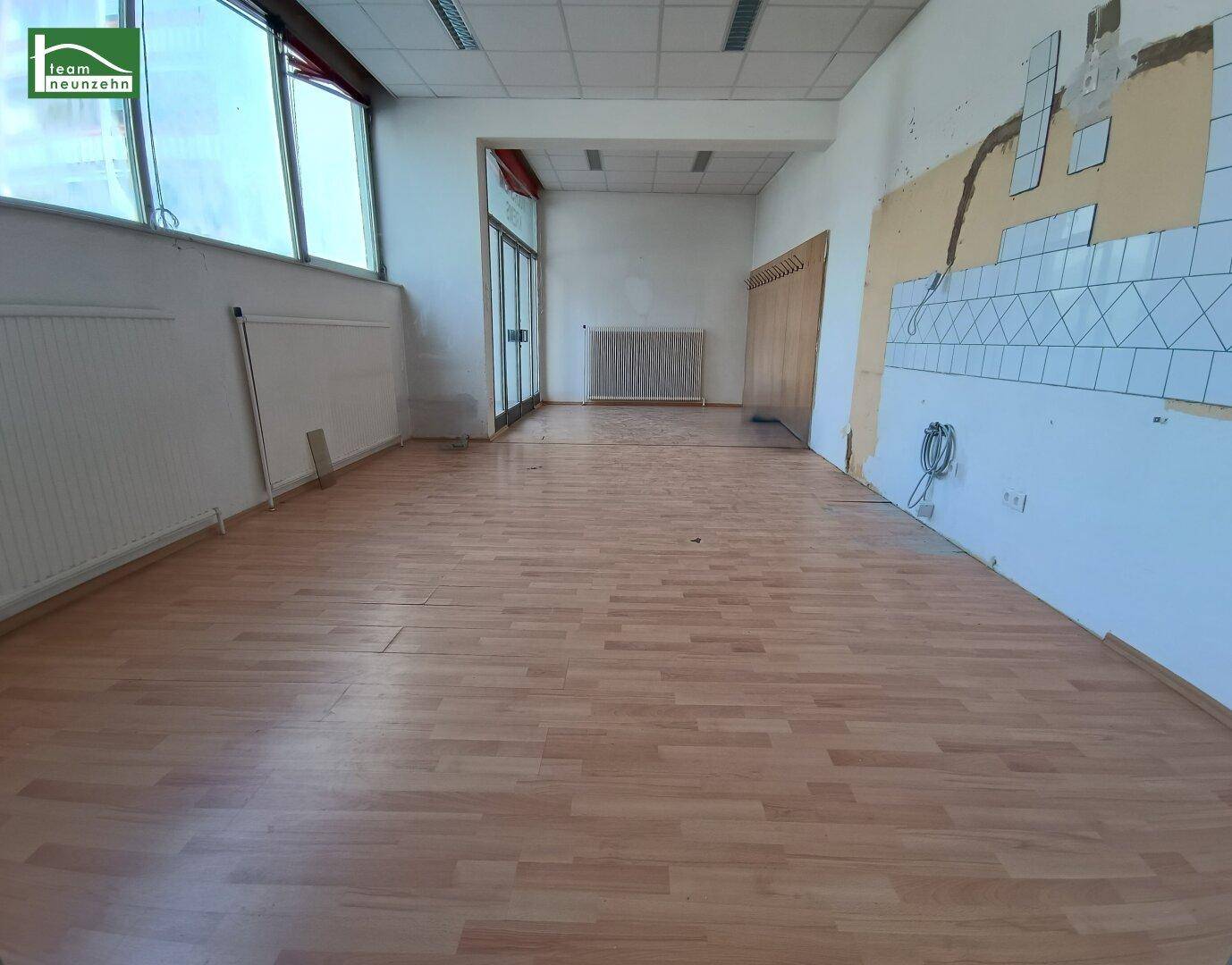Leerer Raum mit hellem Laminatboden und Spuren einer ehemaligen Wandverkleidung.