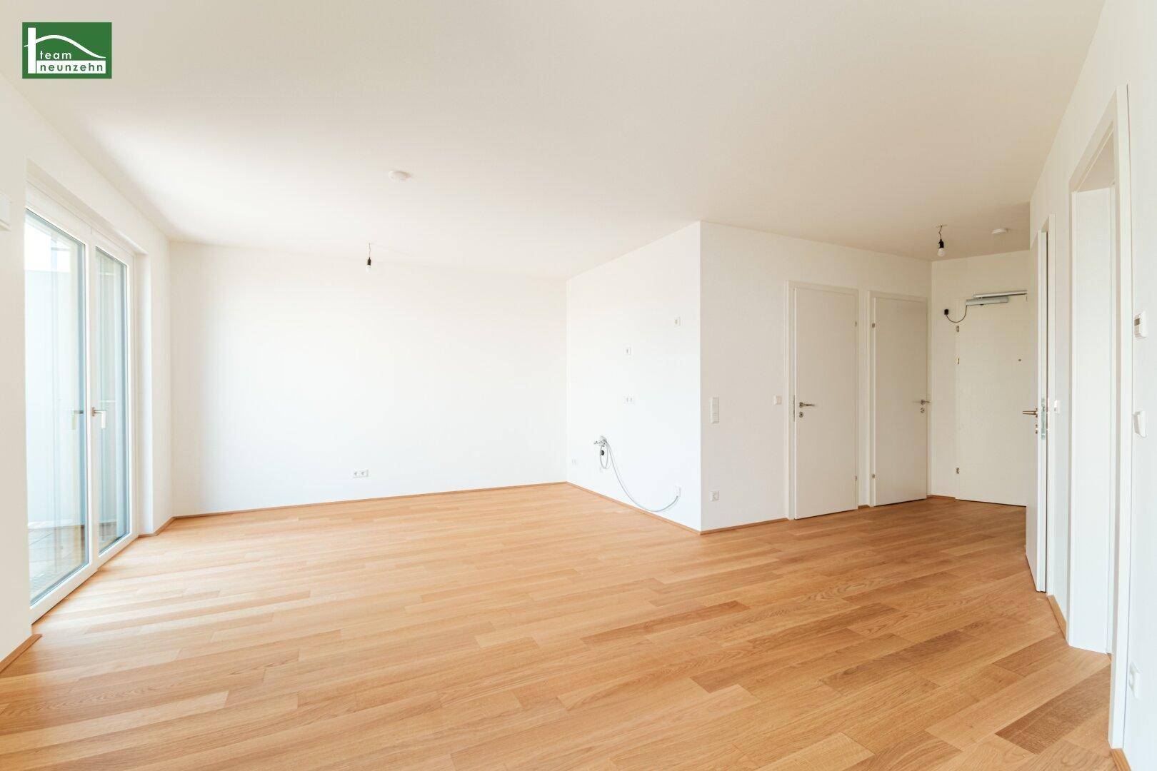 Großes, helles Zimmer mit Holzboden und mehreren Türen, ideal als Wohnbereich.