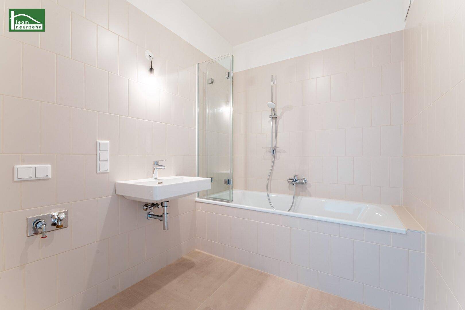 Modernes Badezimmer mit Badewanne, Duschabtrennung und hellem Fliesenboden.