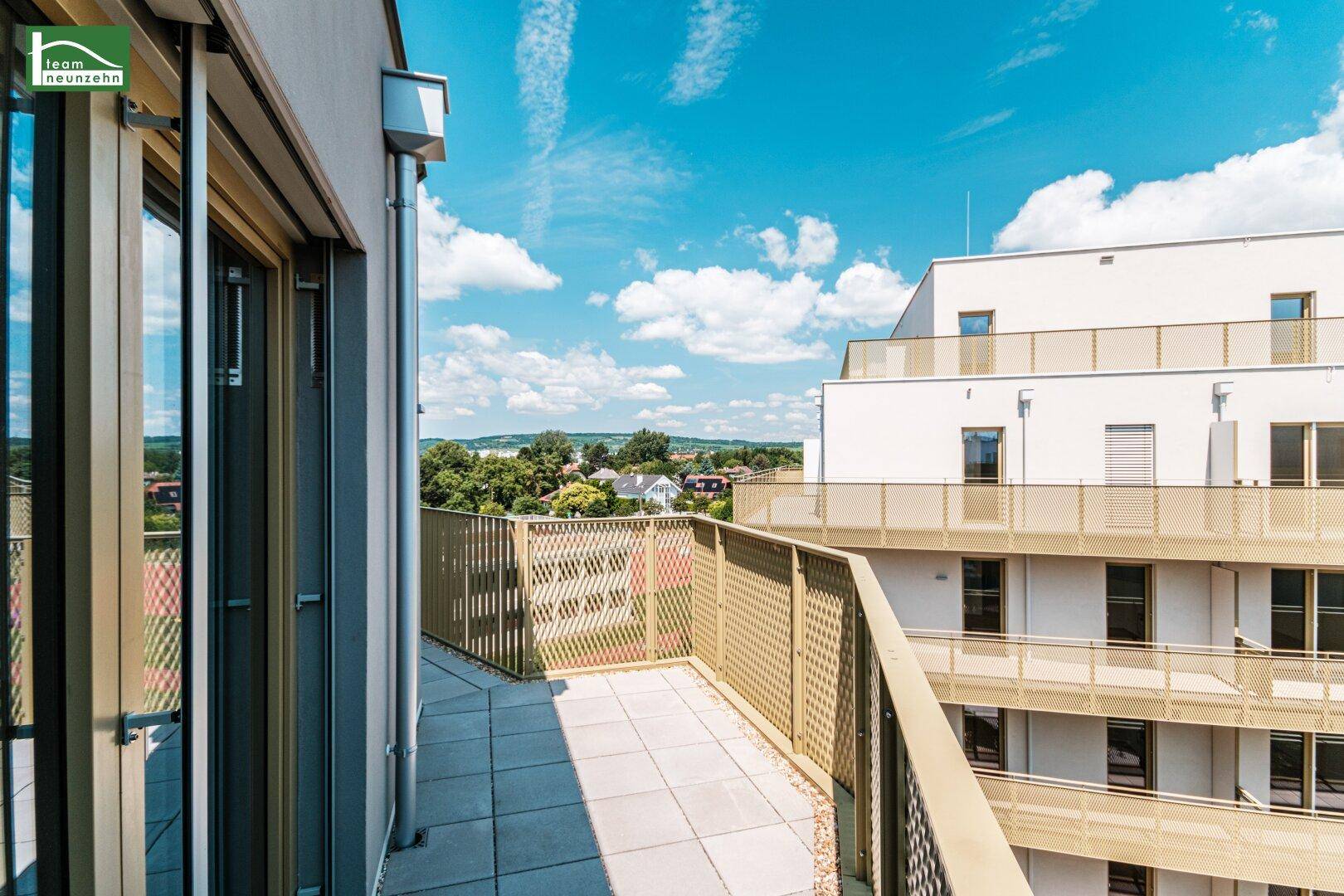 Weitläufige Terrasse mit sonnigem Ausblick über die Dächer und die grüne Umgebung.