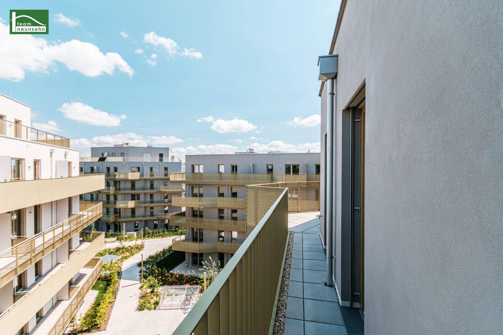 Geräumige Terrasse mit Blick auf die umliegenden modernen Wohngebäude und den Innenhof.