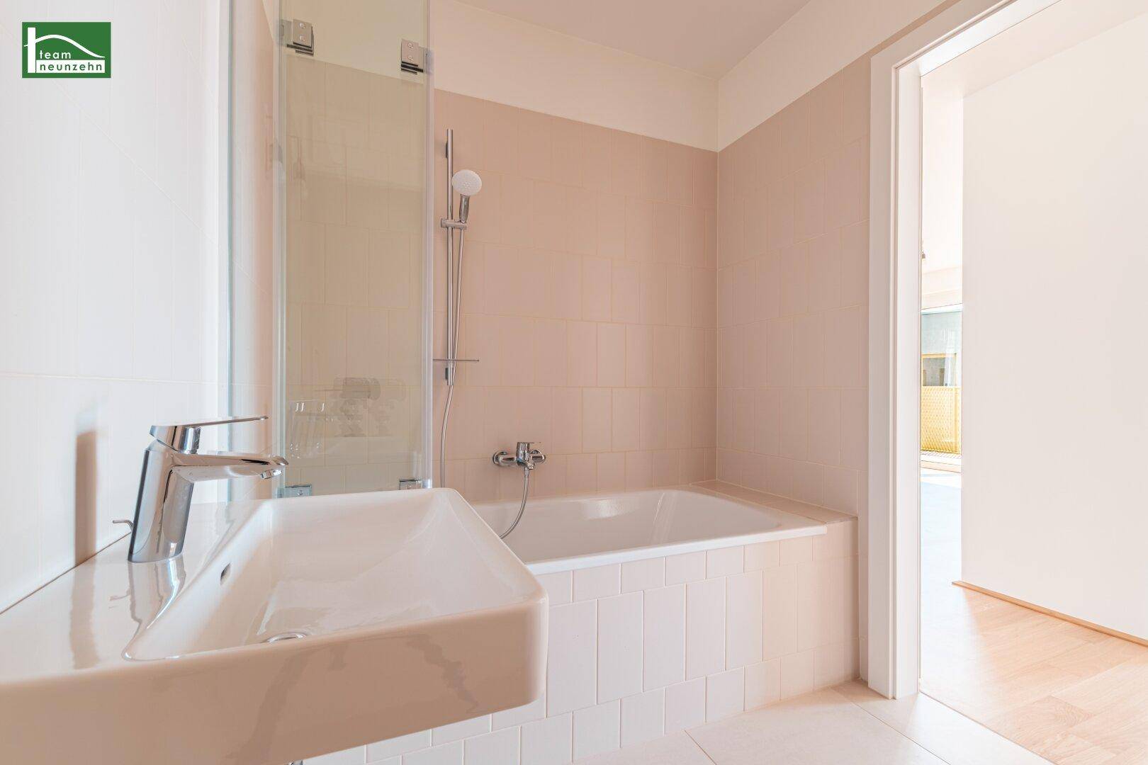 Helles Badezimmer mit Badewanne, Duscharmatur und modernem Waschbecken.