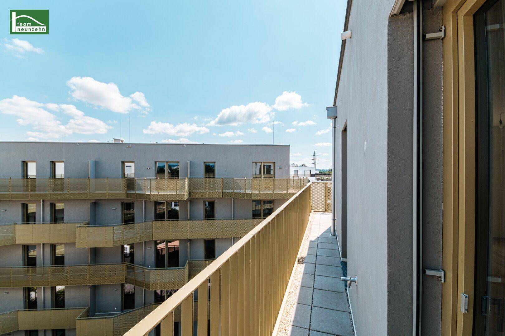 Langer Balkon mit Metallgeländer und Blick auf die umliegenden Gebäude.