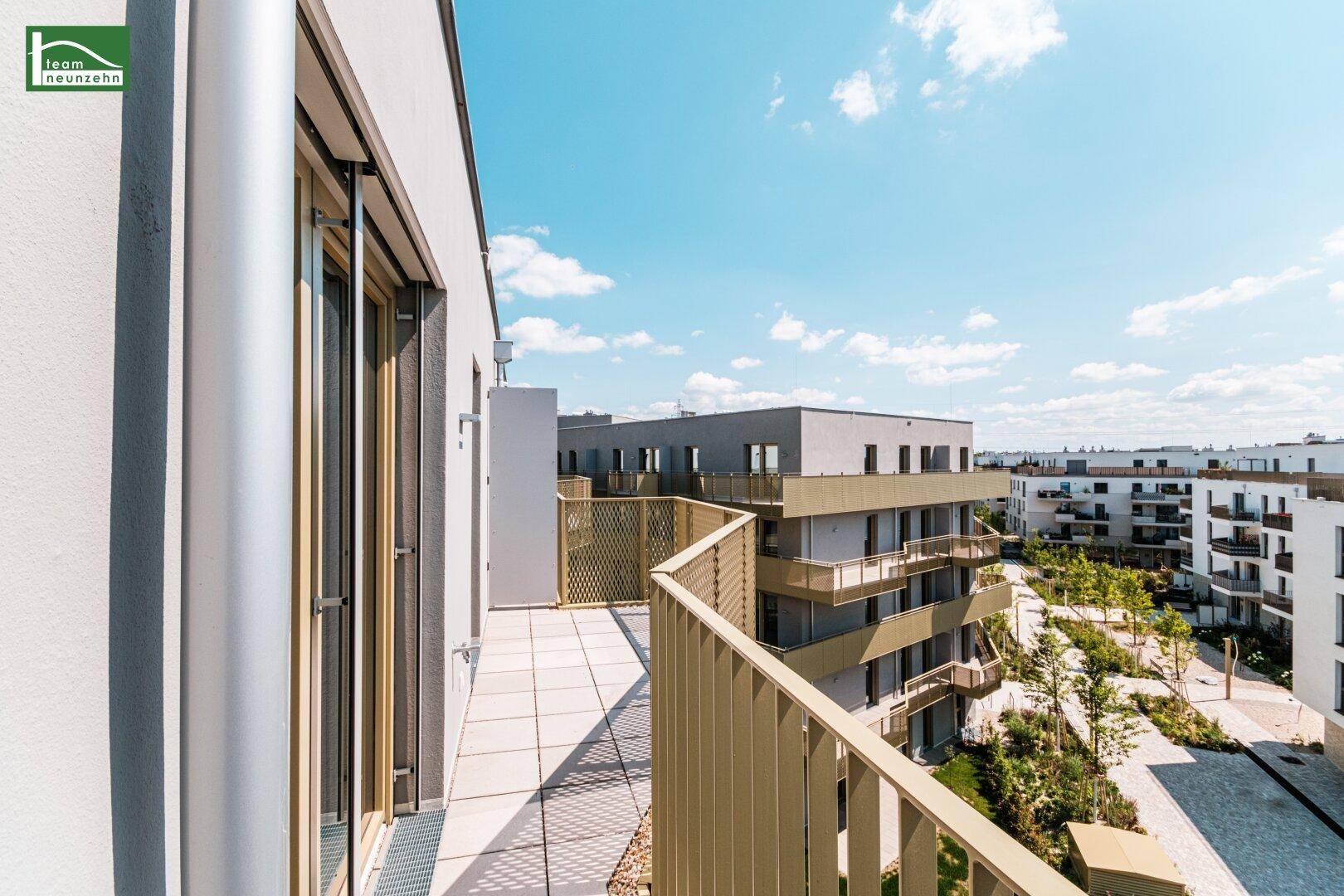 Geräumiger Balkon mit moderner Metallbrüstung und Blick auf die umliegenden Neubauten und Grünflächen.