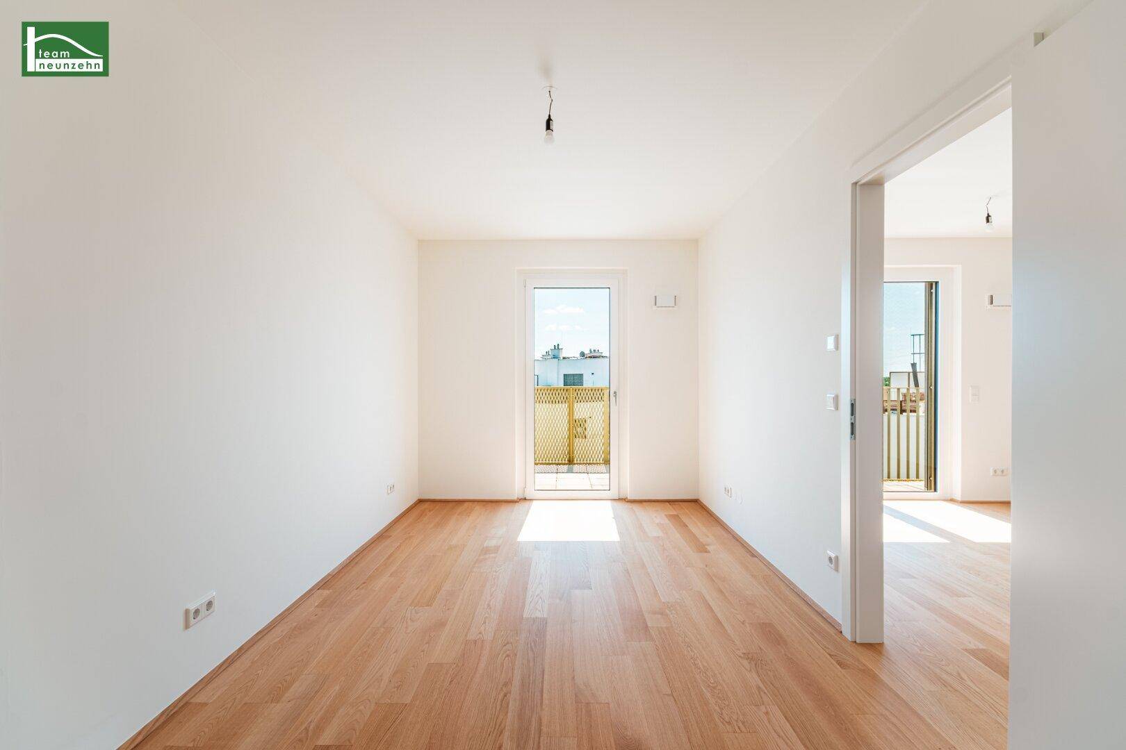 Lichtdurchflutetes Zimmer mit Holzboden und Balkonzugang, bereit für individuelle Gestaltung.
