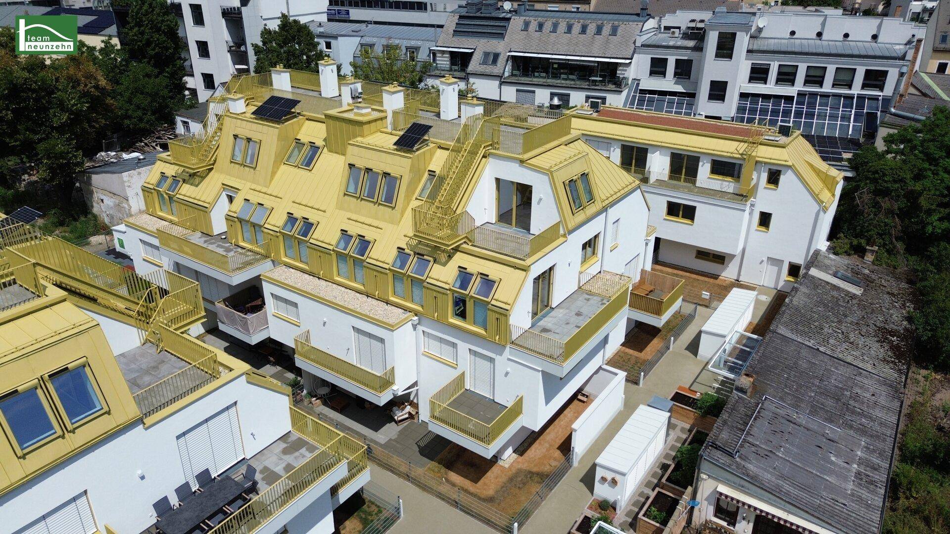 Luftaufnahme eines modernen Wohngebäudes mit gelben Akzenten und Dachterrassen.