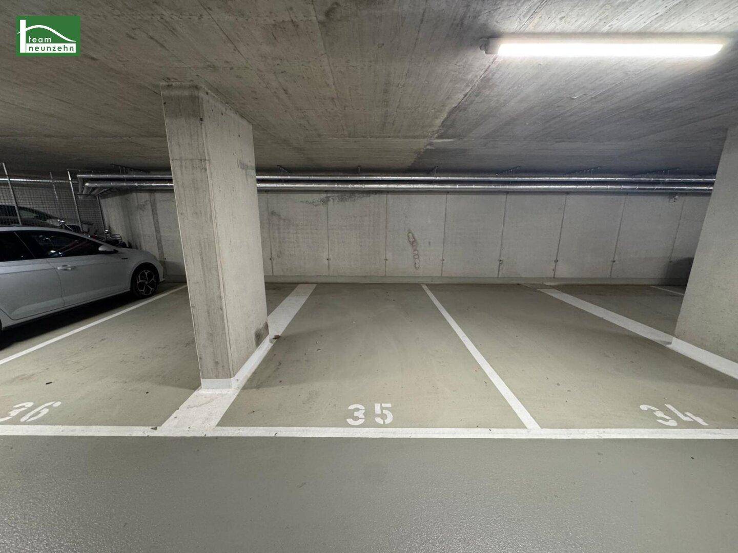 Leerer, sauberer Parkplatz in einer Tiefgarage mit nummerierten Stellflächen und grauen Betonwänden.