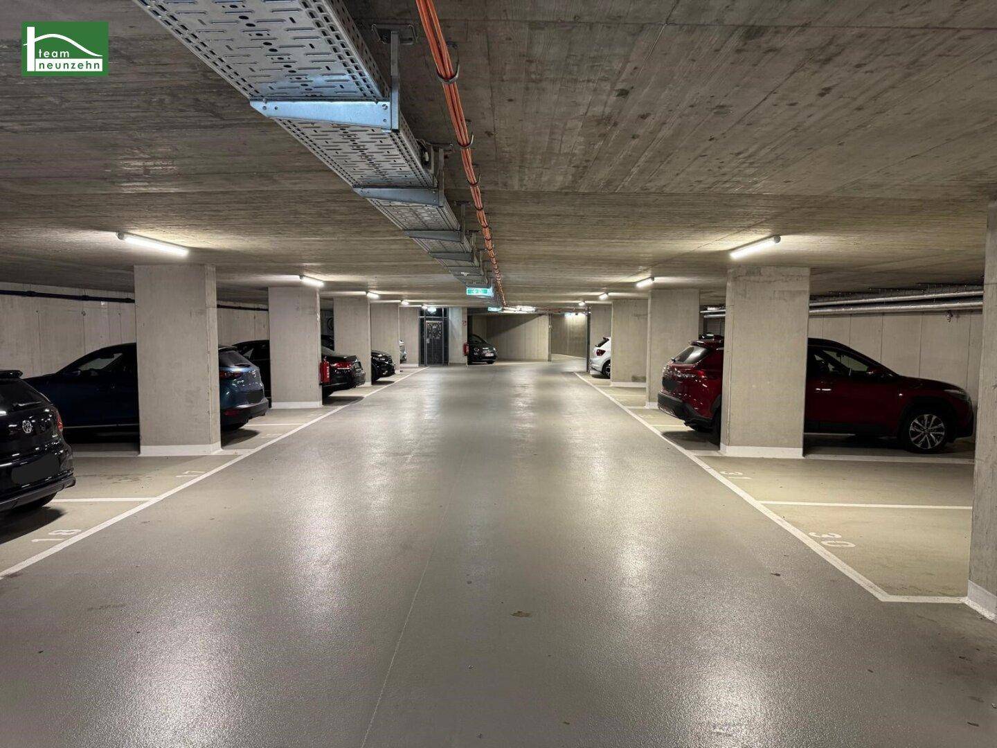 Geräumige Tiefgarage mit mehreren geparkten Fahrzeugen und moderner Beleuchtung.