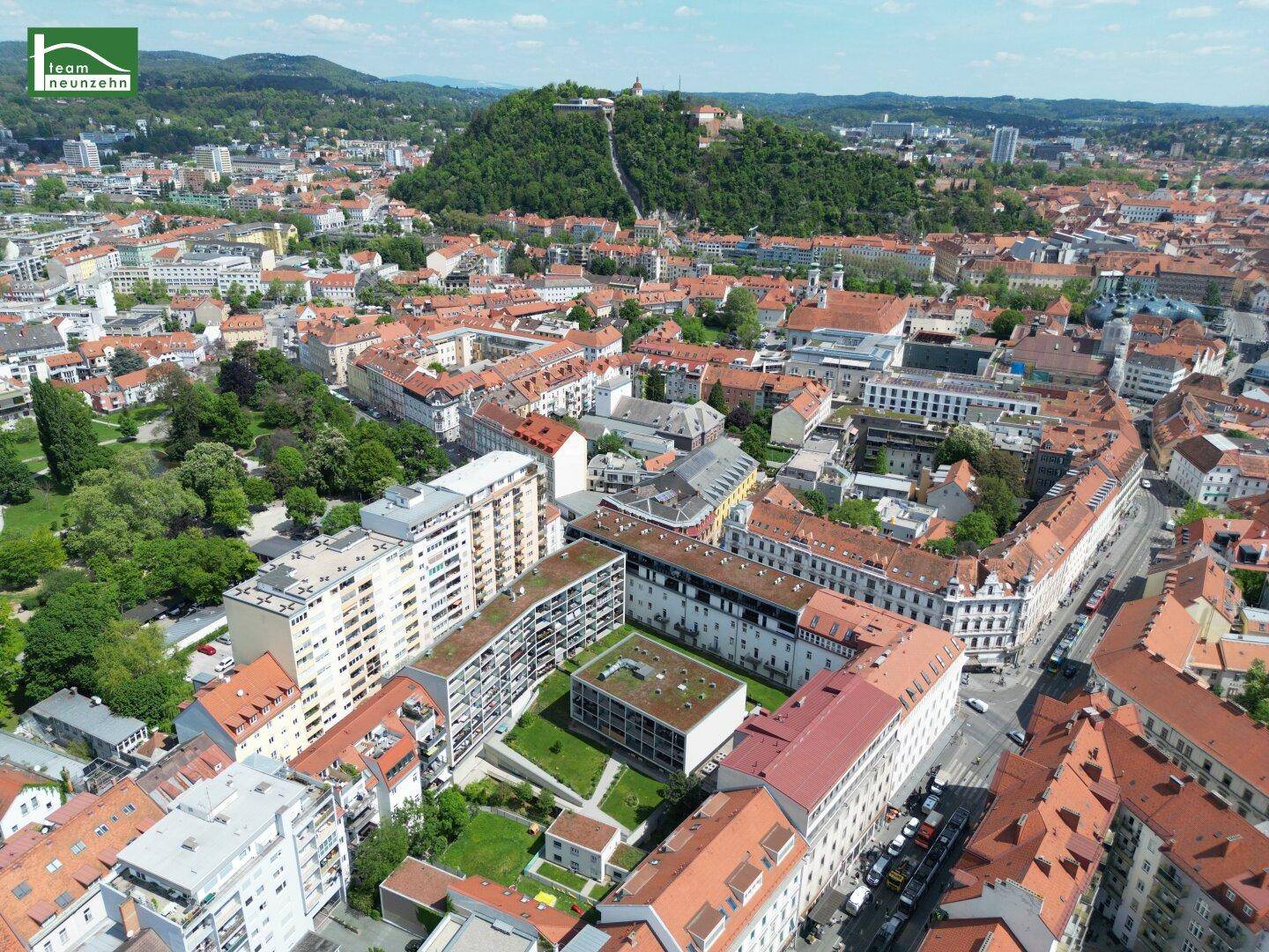 Luftaufnahme der Stadt Graz mit dem Schlossberg und umliegenden Wohngebäuden.