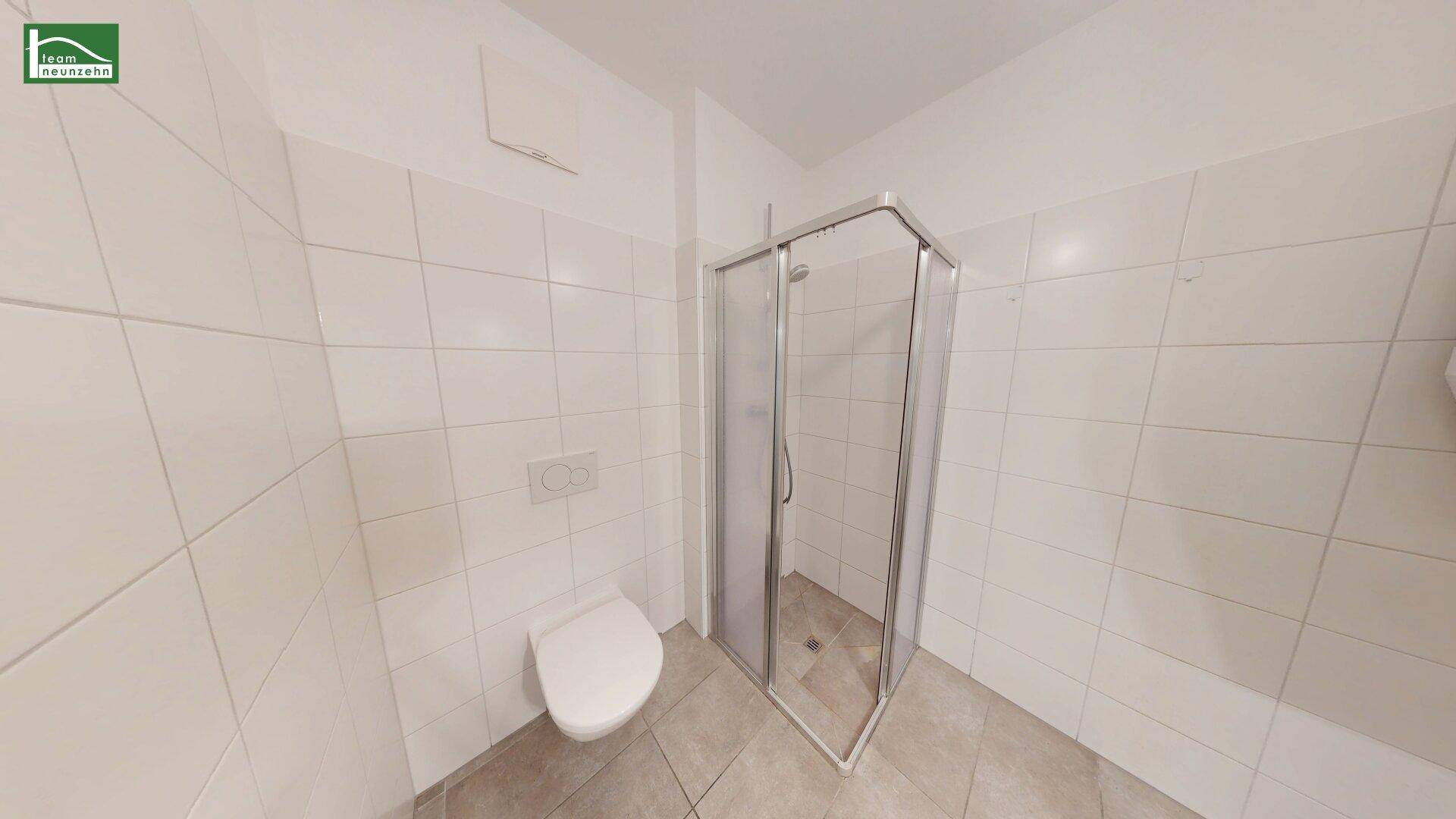 Funktionales Badezimmer mit Duschkabine, Toilette und hellen Wandfliesen.