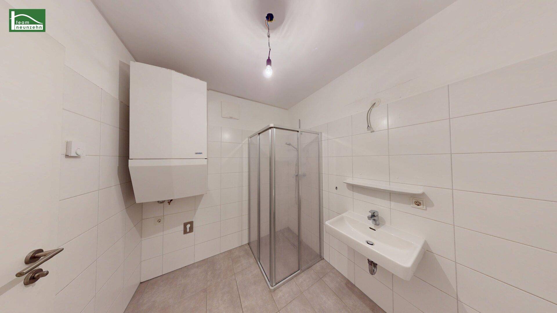 Modernes Badezimmer mit Dusche, Waschbecken und weiß gefliesten Wänden.
