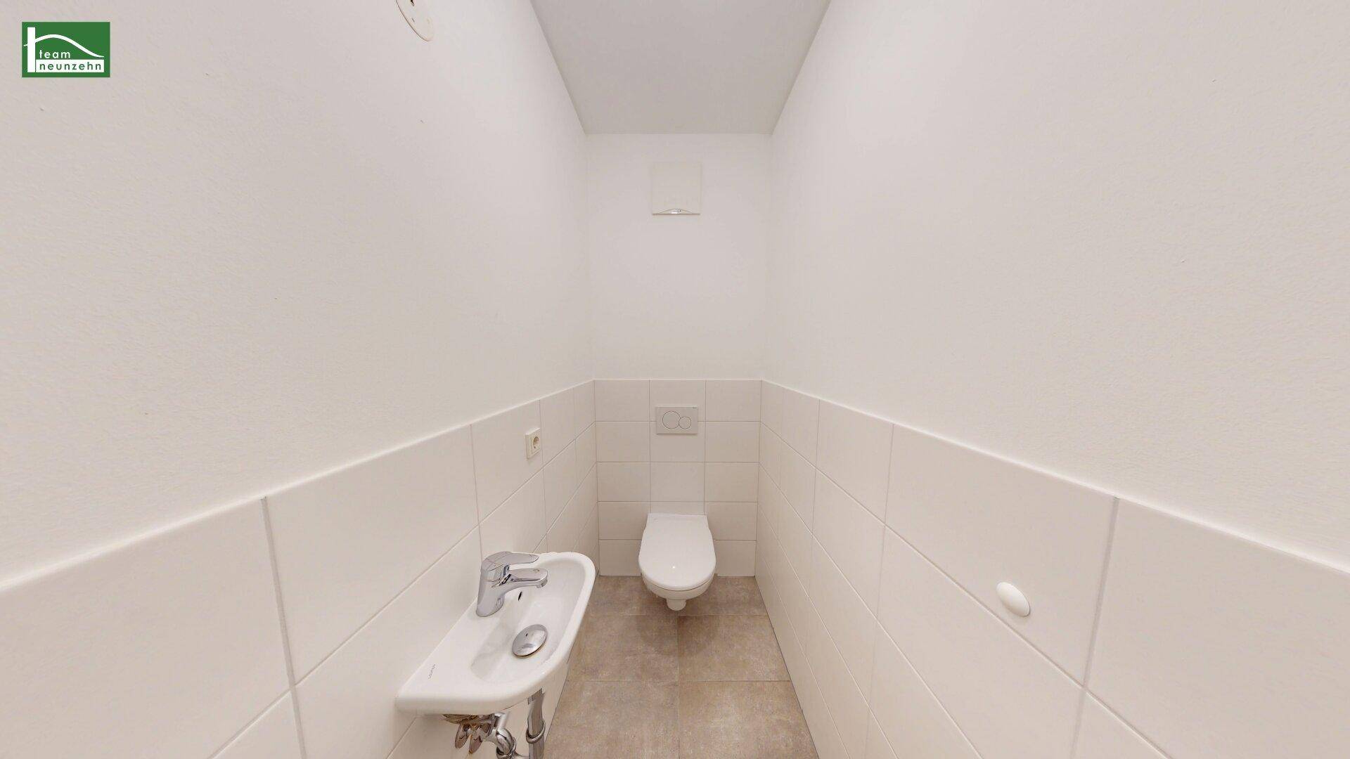 Separates Gäste-WC mit wandhängendem WC und kleinem Handwaschbecken.