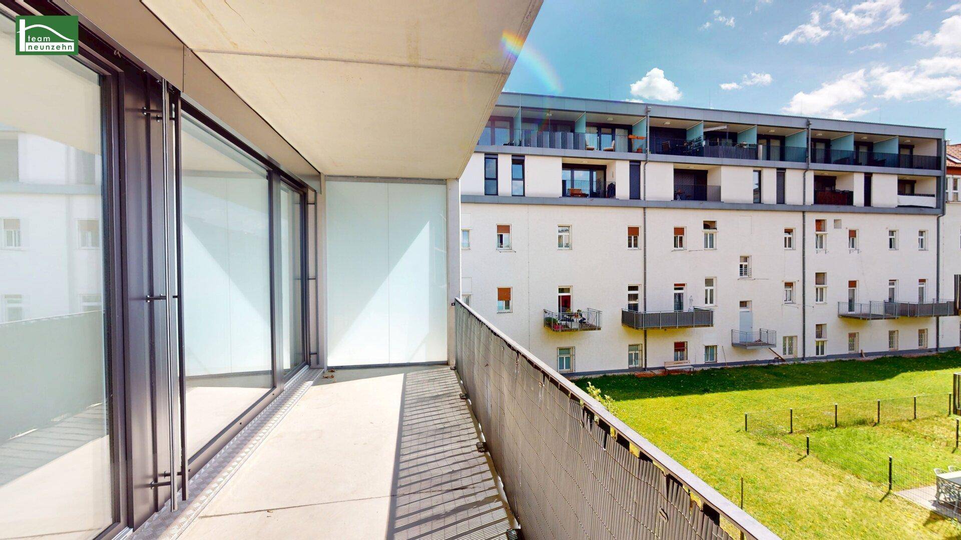 Geräumiger Balkon mit Metallgeländer und Blick auf die umliegenden Gebäude und Grünflächen.