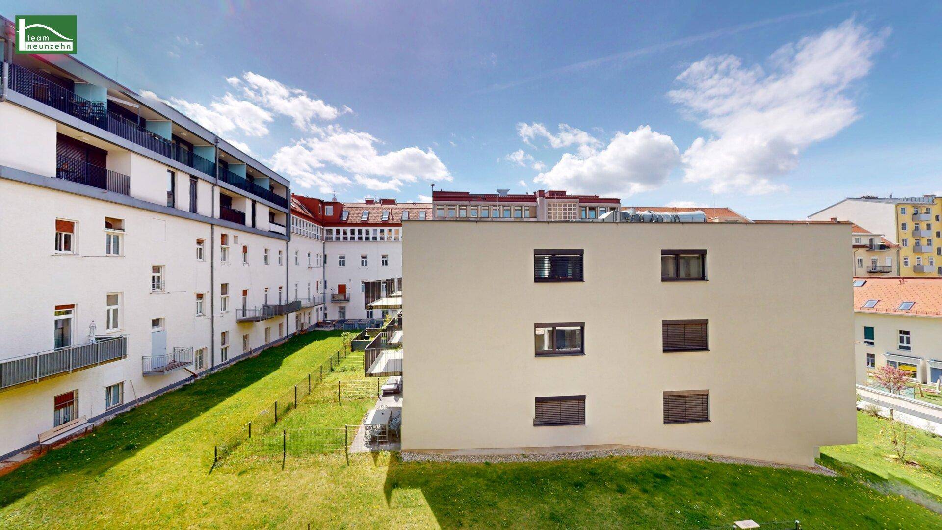Außenansicht eines modernen Wohnkomplexes mit gepflegten Grünflächen und angrenzenden Gebäuden.